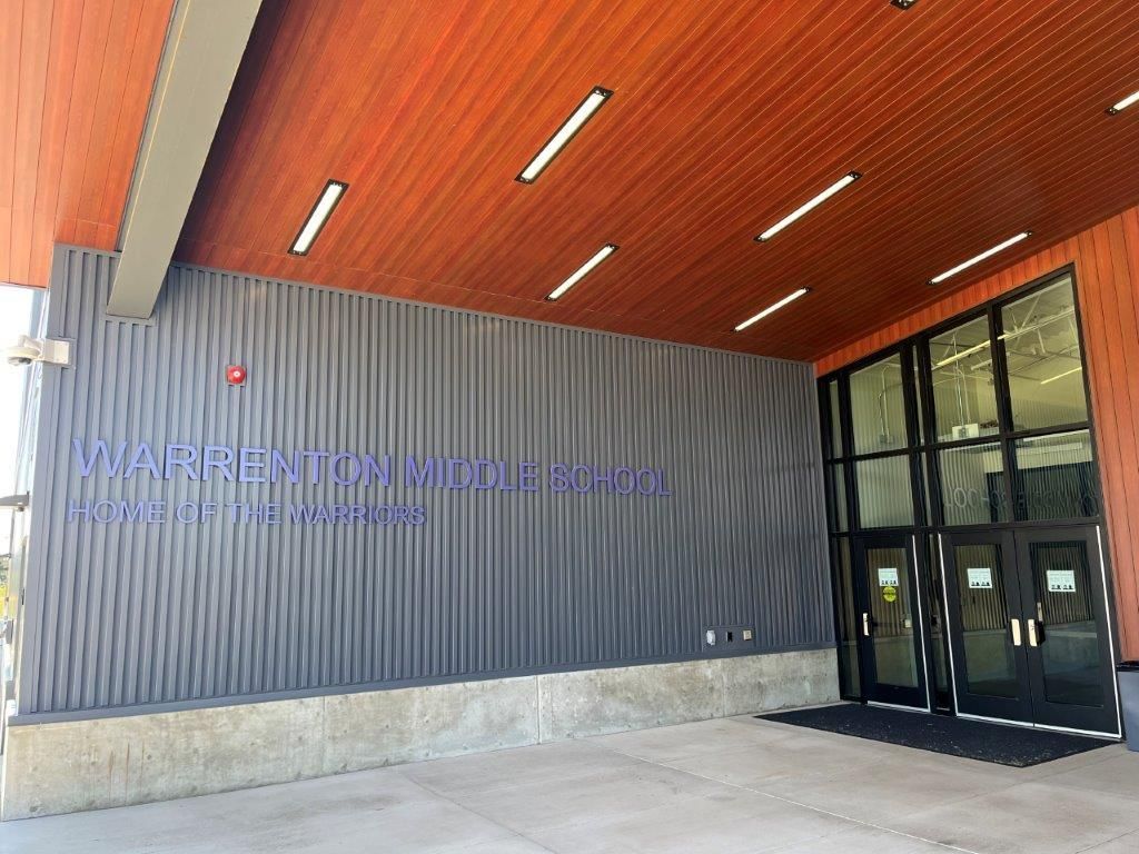 Exterior entrance with red ceiling, gray wall, glass doors, and building signage