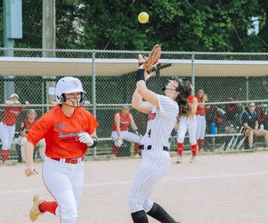 Baseball player sliding into home plate, catcher in front. Blue and gold uniforms, action shot.