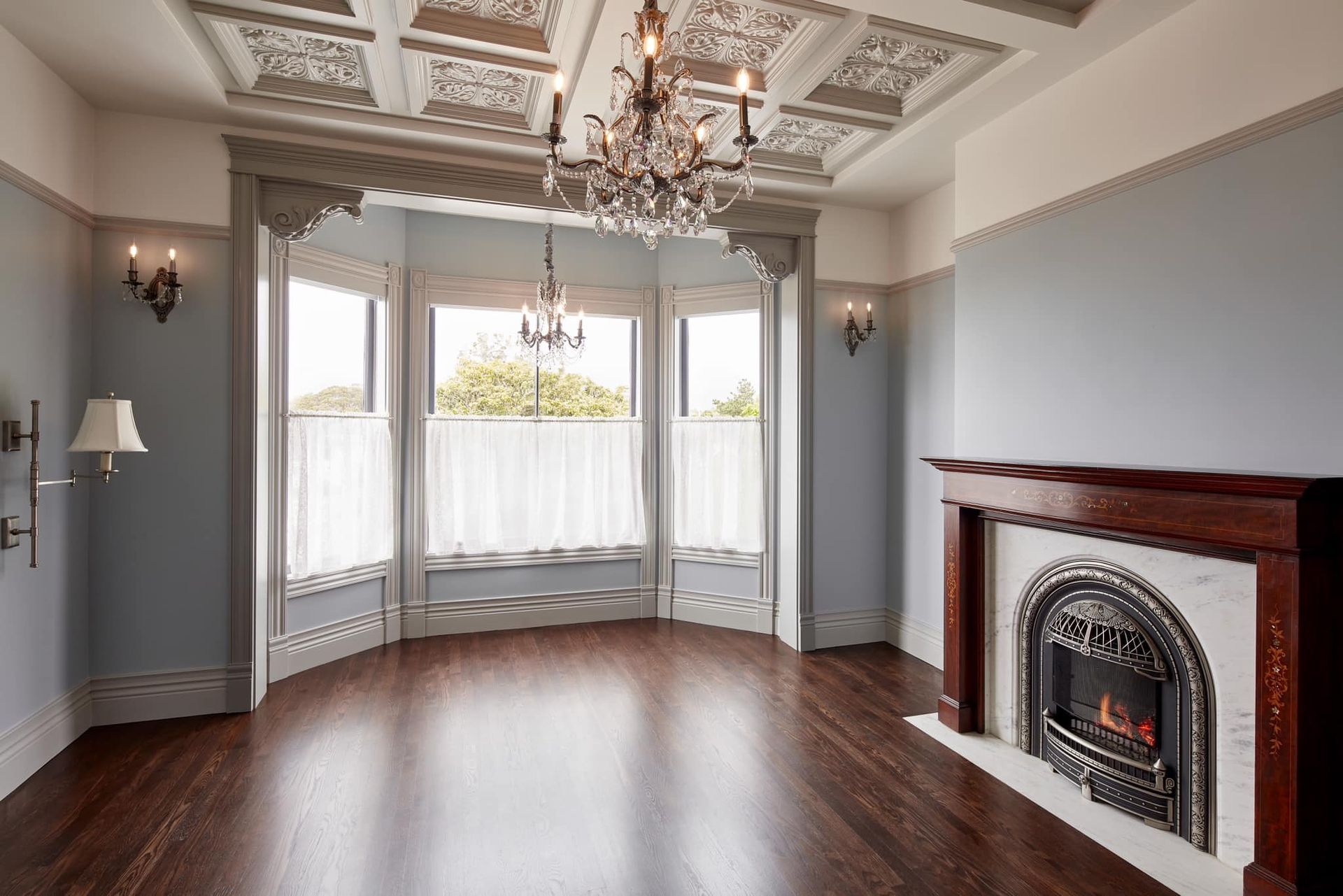 An empty living room with a fireplace and a chandelier