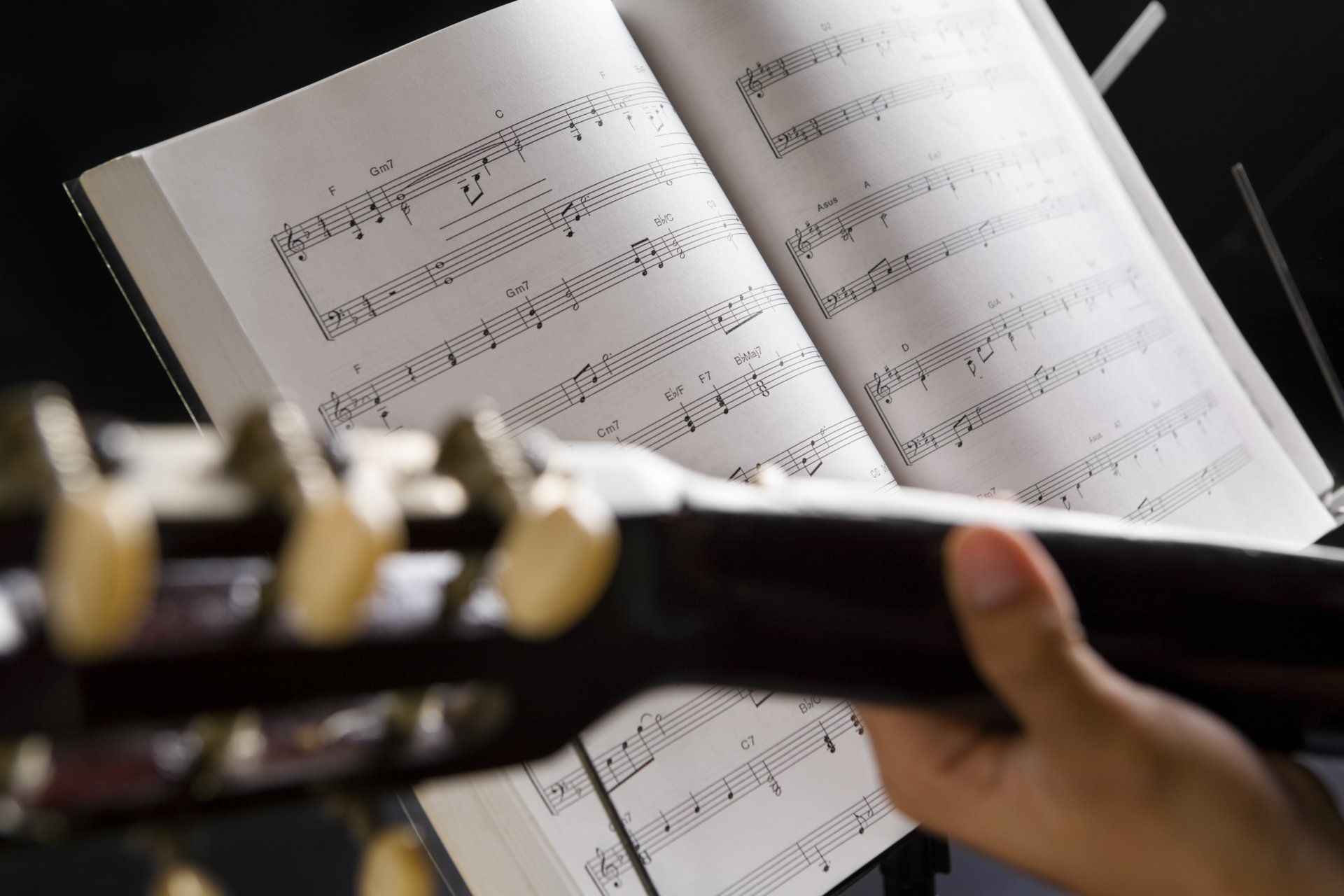 A person is holding a guitar in front of an open music book