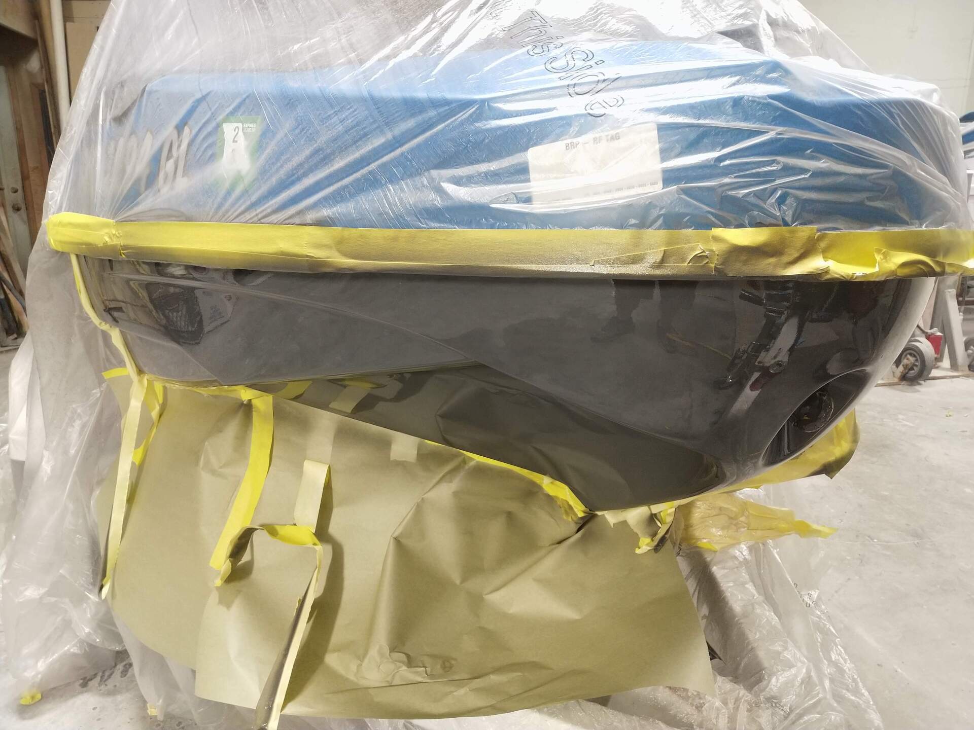 Plastic-wrapped blue and black item with yellow straps, sitting in a clear plastic bag