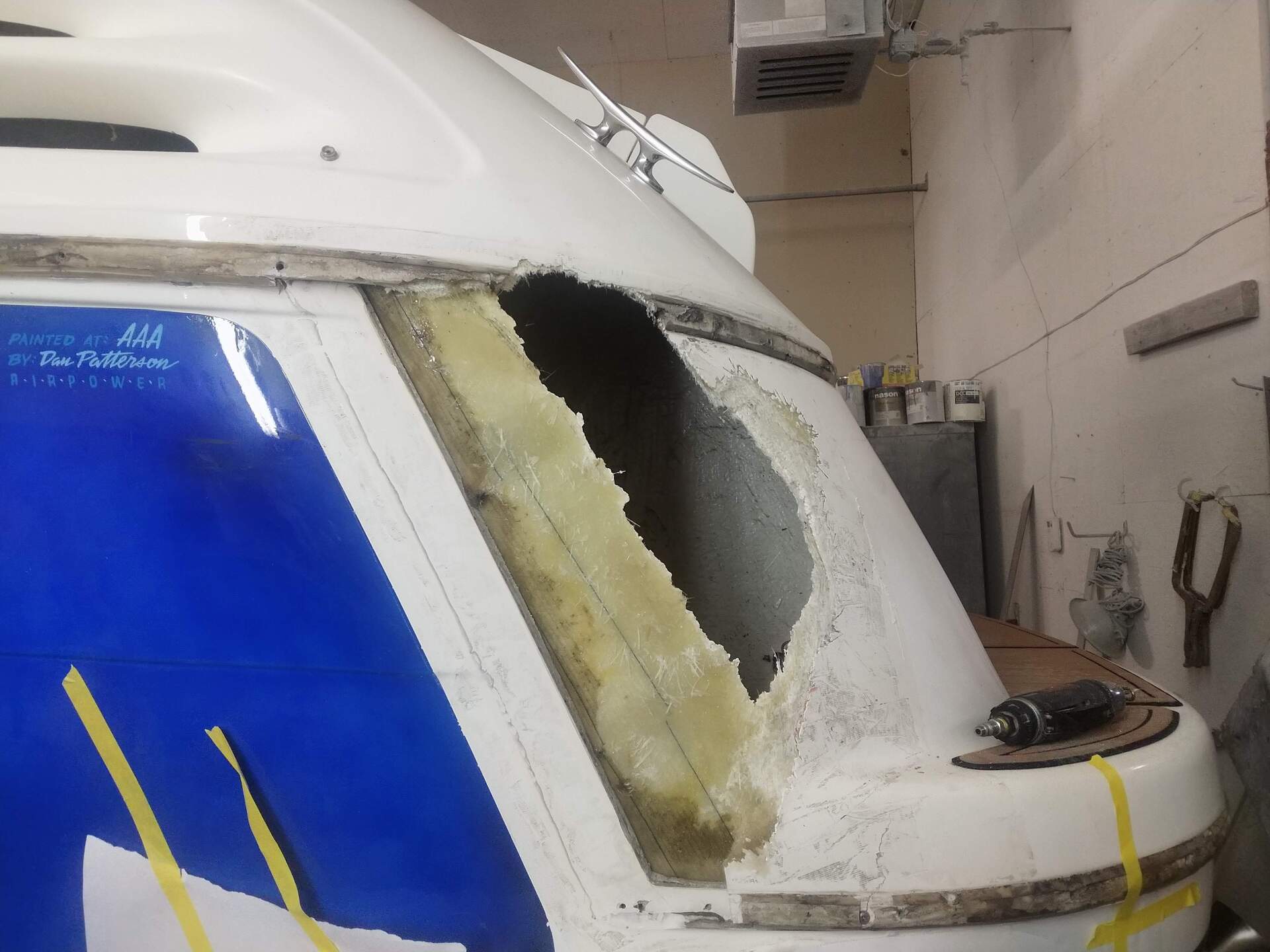 Damaged white van with a large broken rear window and blue tarp covering the side.