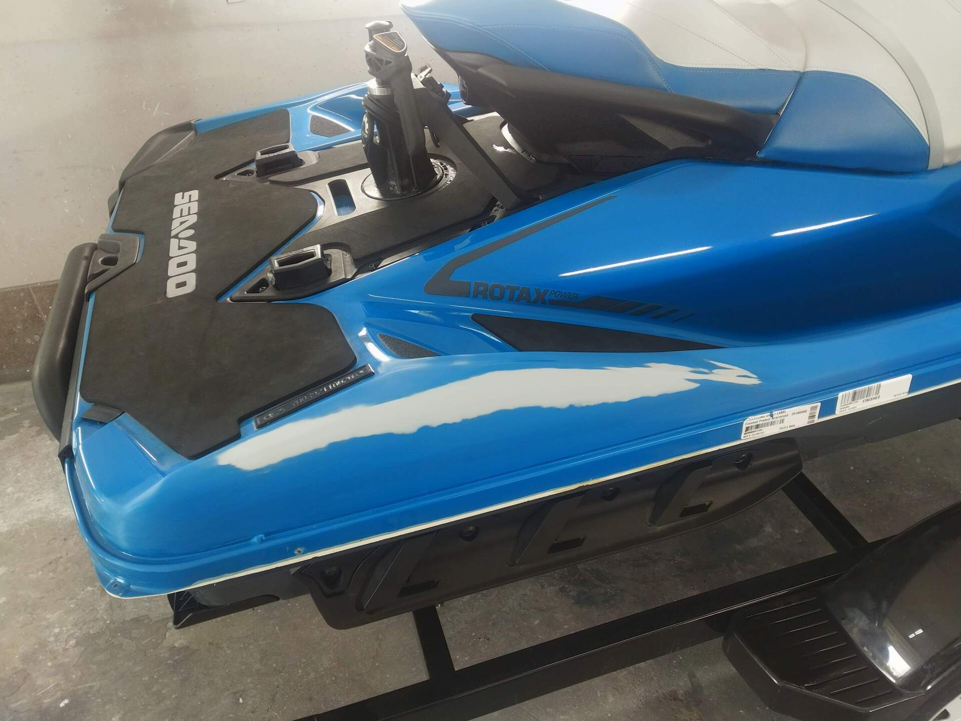 Blue and black jet ski on a black stand in a garage or workshop