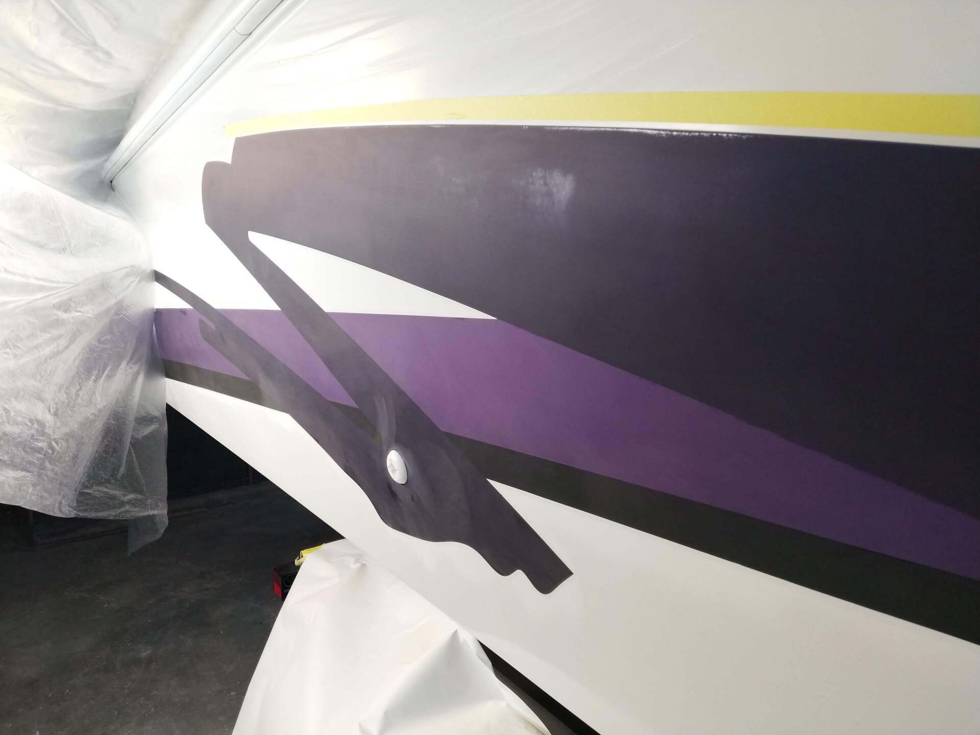Close-up of a purple and black abstract design on a white surface, partly covered with plastic wrap