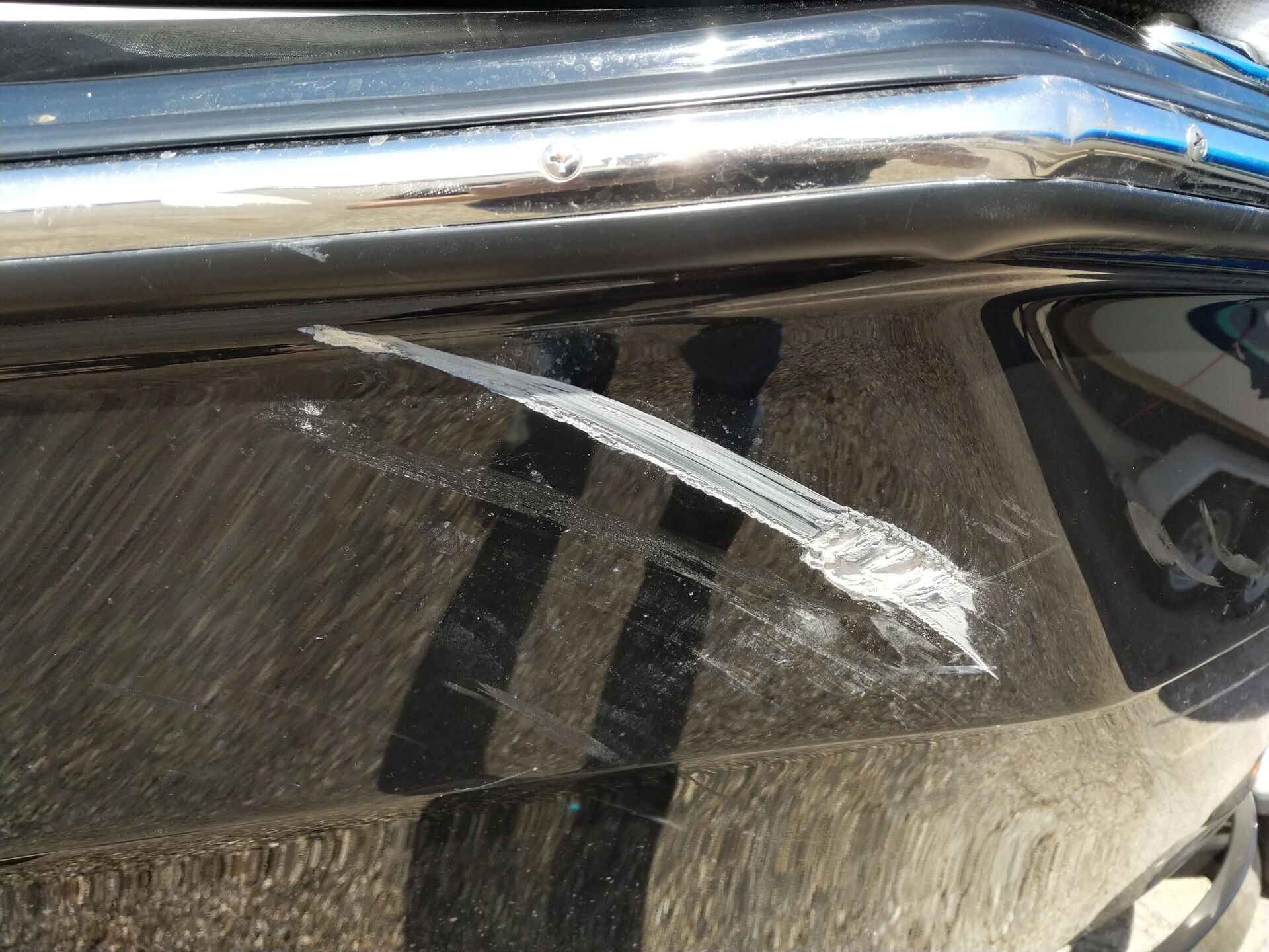 Scratched chrome trim above a dusty car window with a white mark on the glass