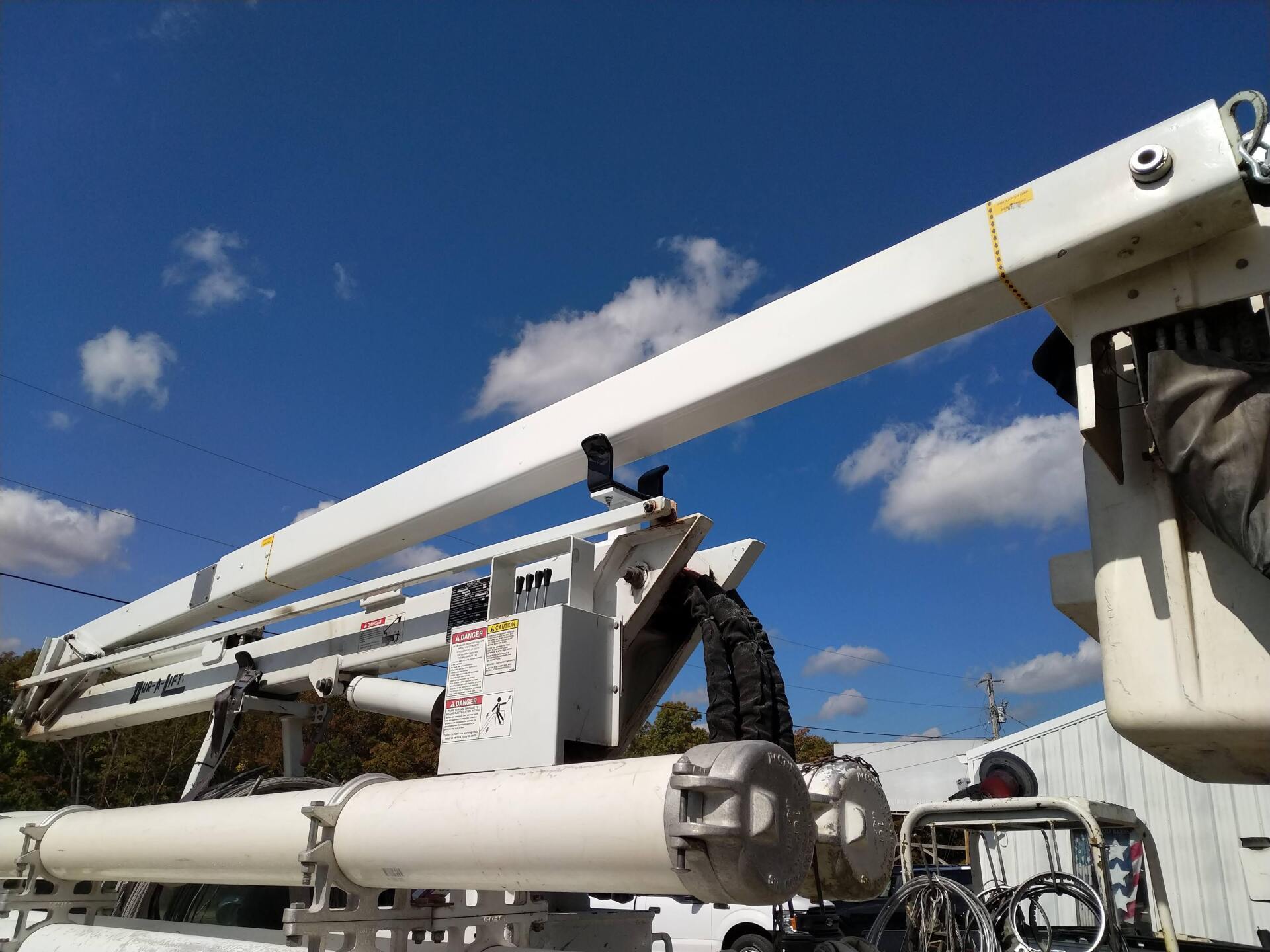 White crane arm with bucket lift under a blue sky with clouds
