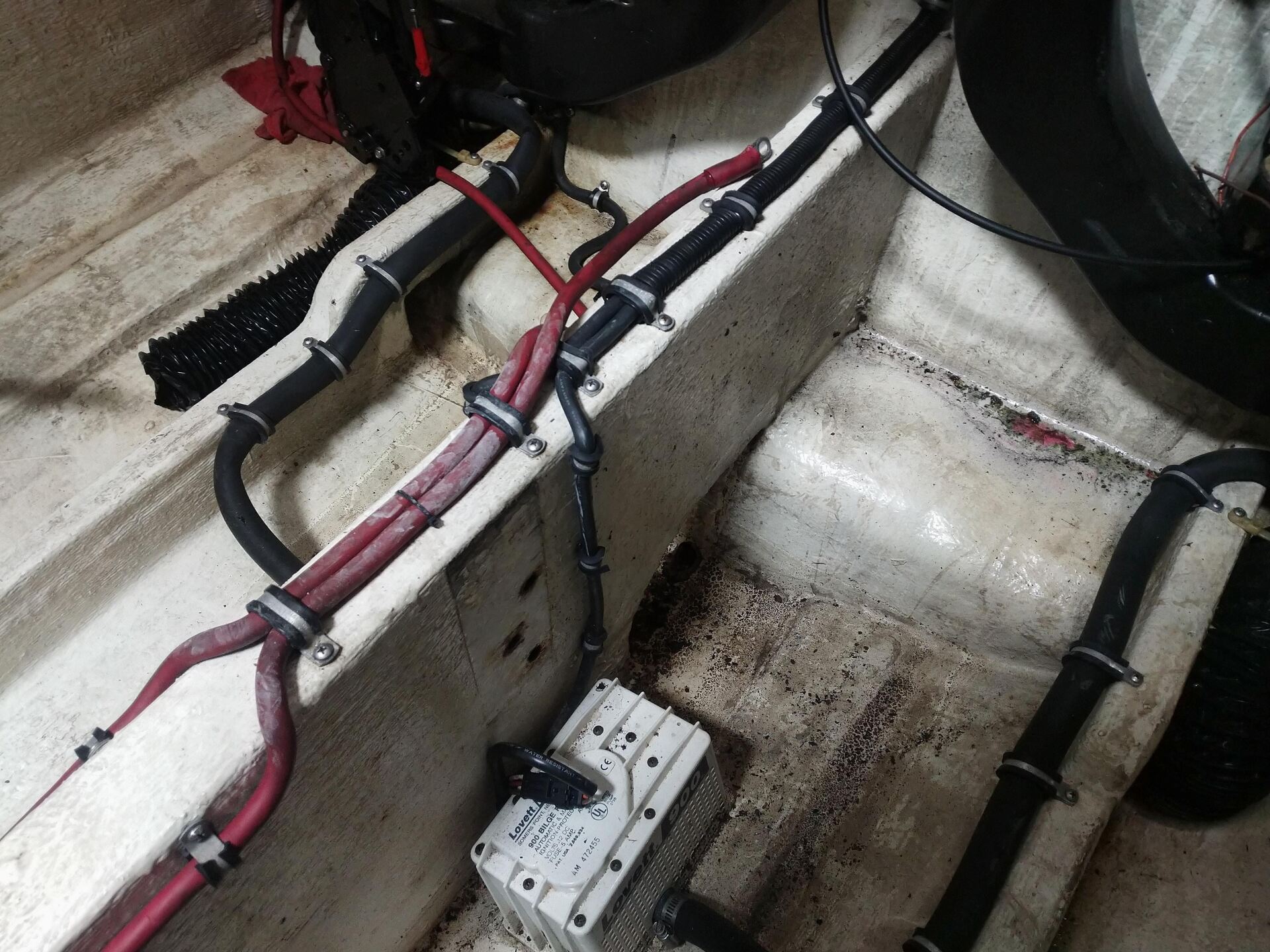Electrical wiring and a fuse box installed inside a white boat hull compartment
