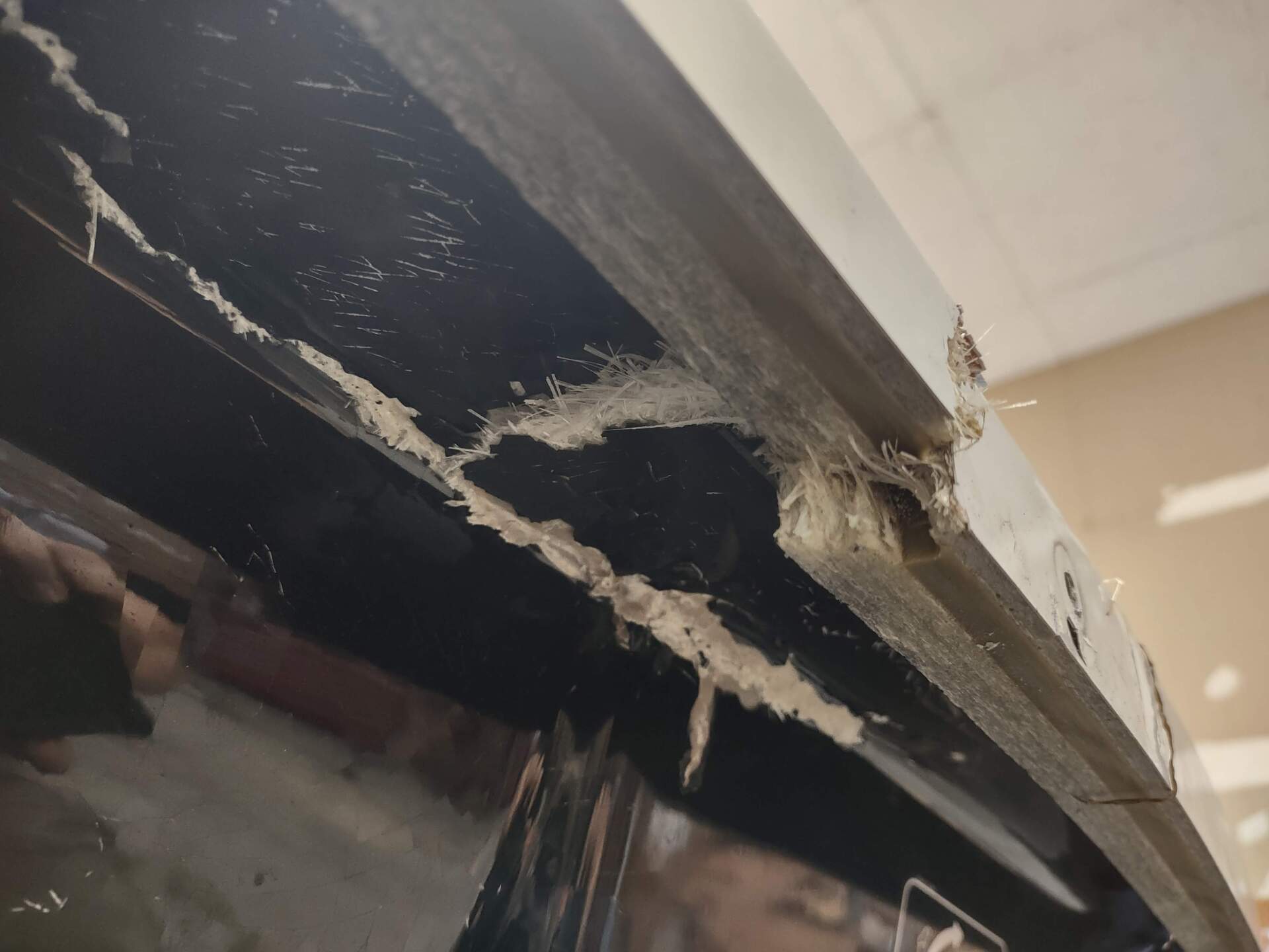 Damaged ceiling edge with peeling material and exposed dark interior gap