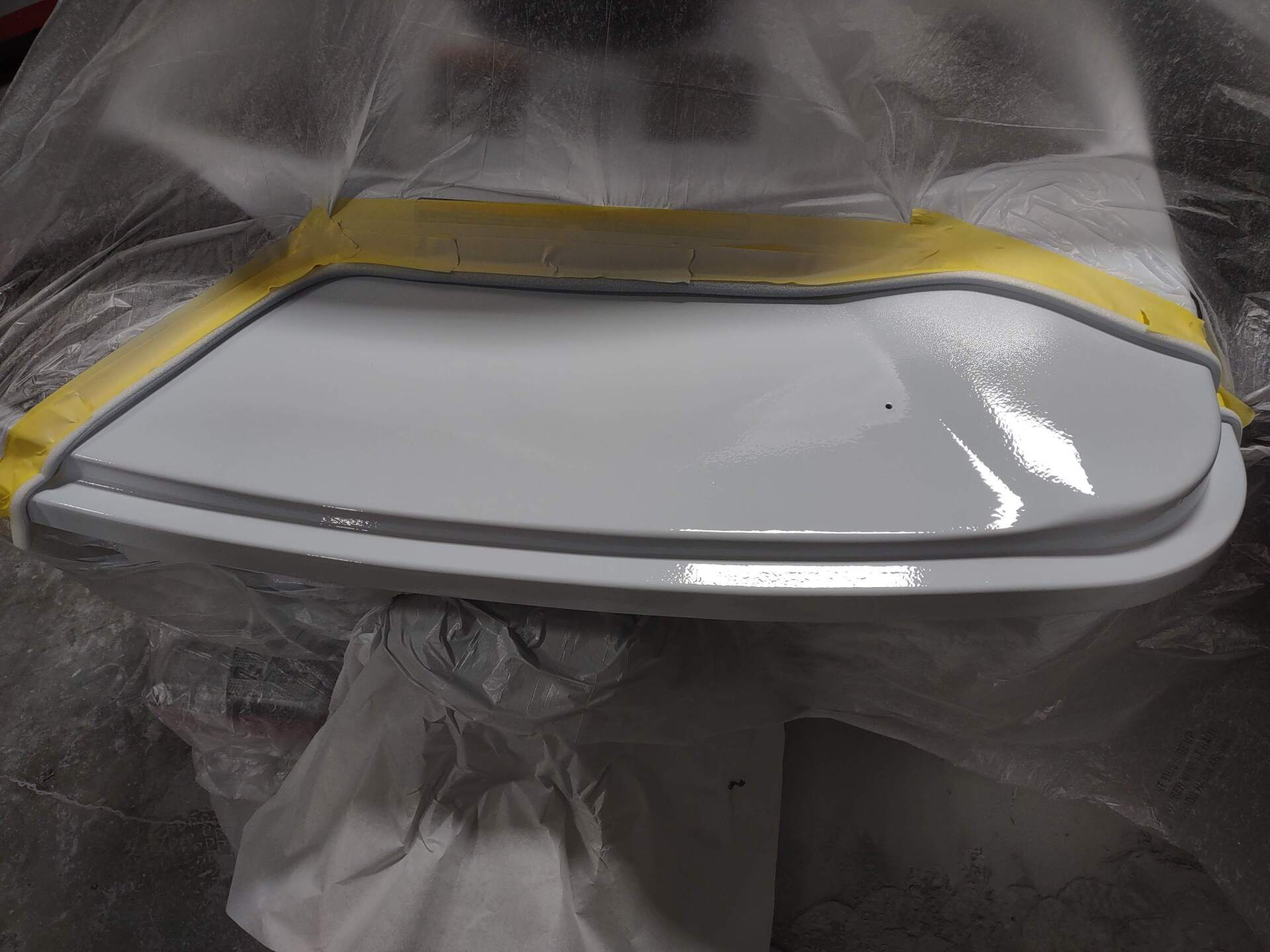 White object wrapped in plastic with a yellow edge, lying on a dark surface