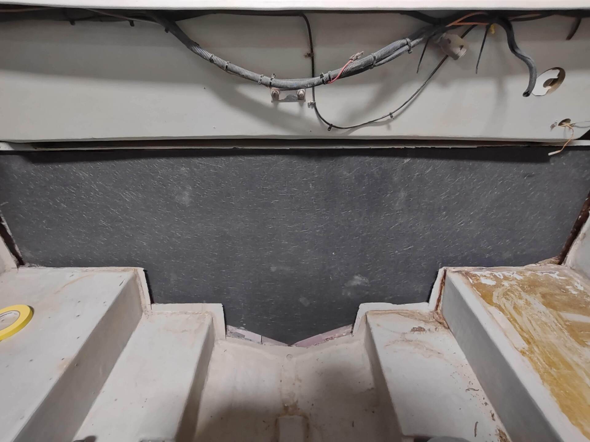 Damaged interior stairwell with exposed wiring and a dark, worn wall panel.