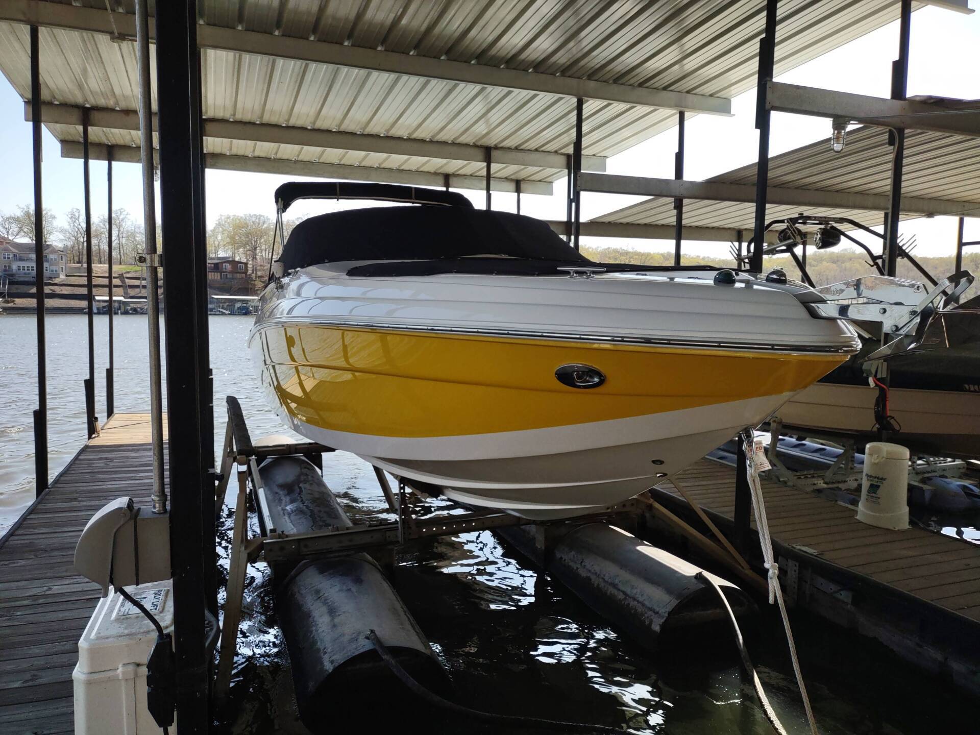 White and yellow boat on a lift in a covered dock beside the water