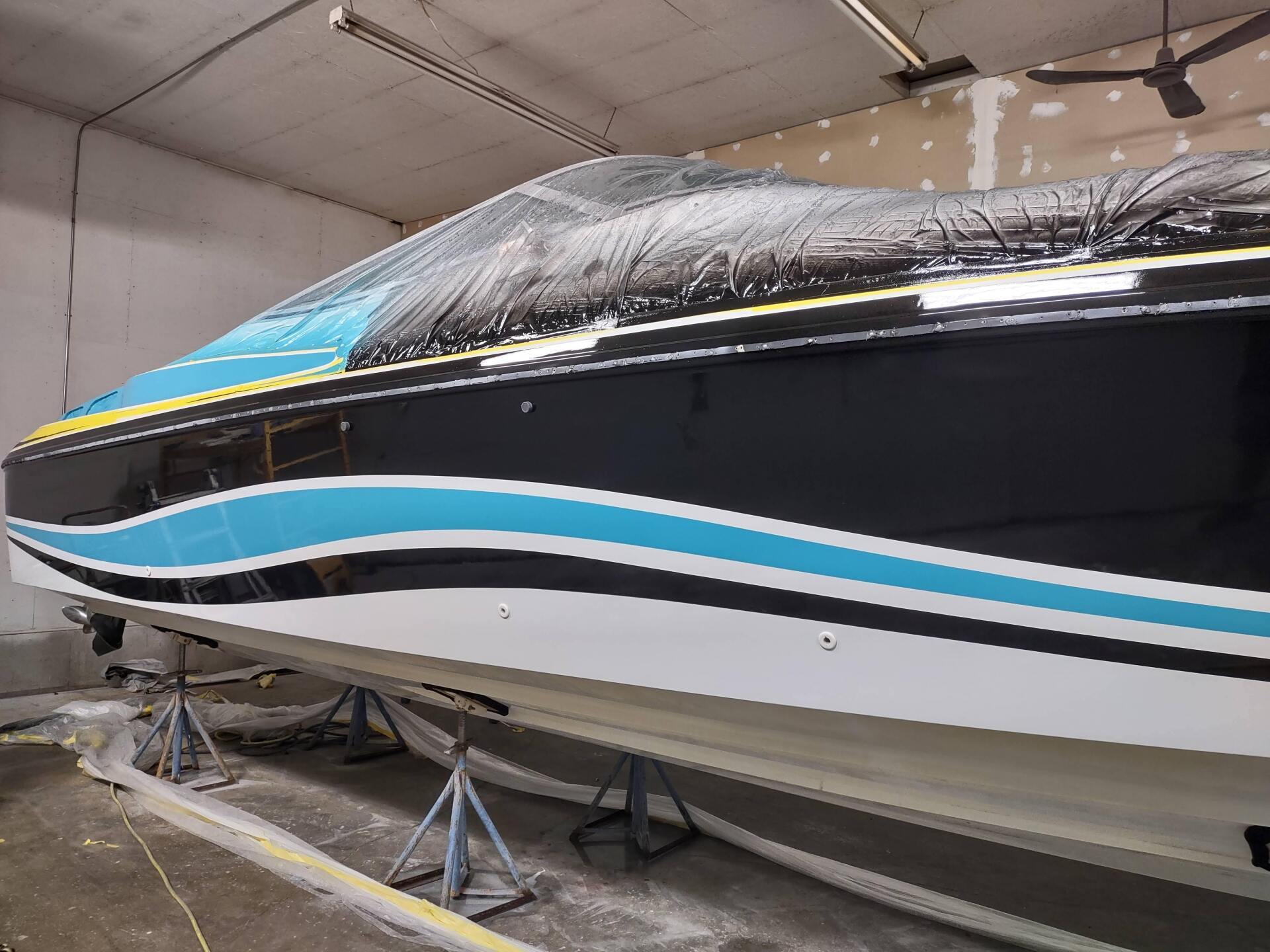 Black and white boat with blue stripe, covered in a garage on stands for maintenance