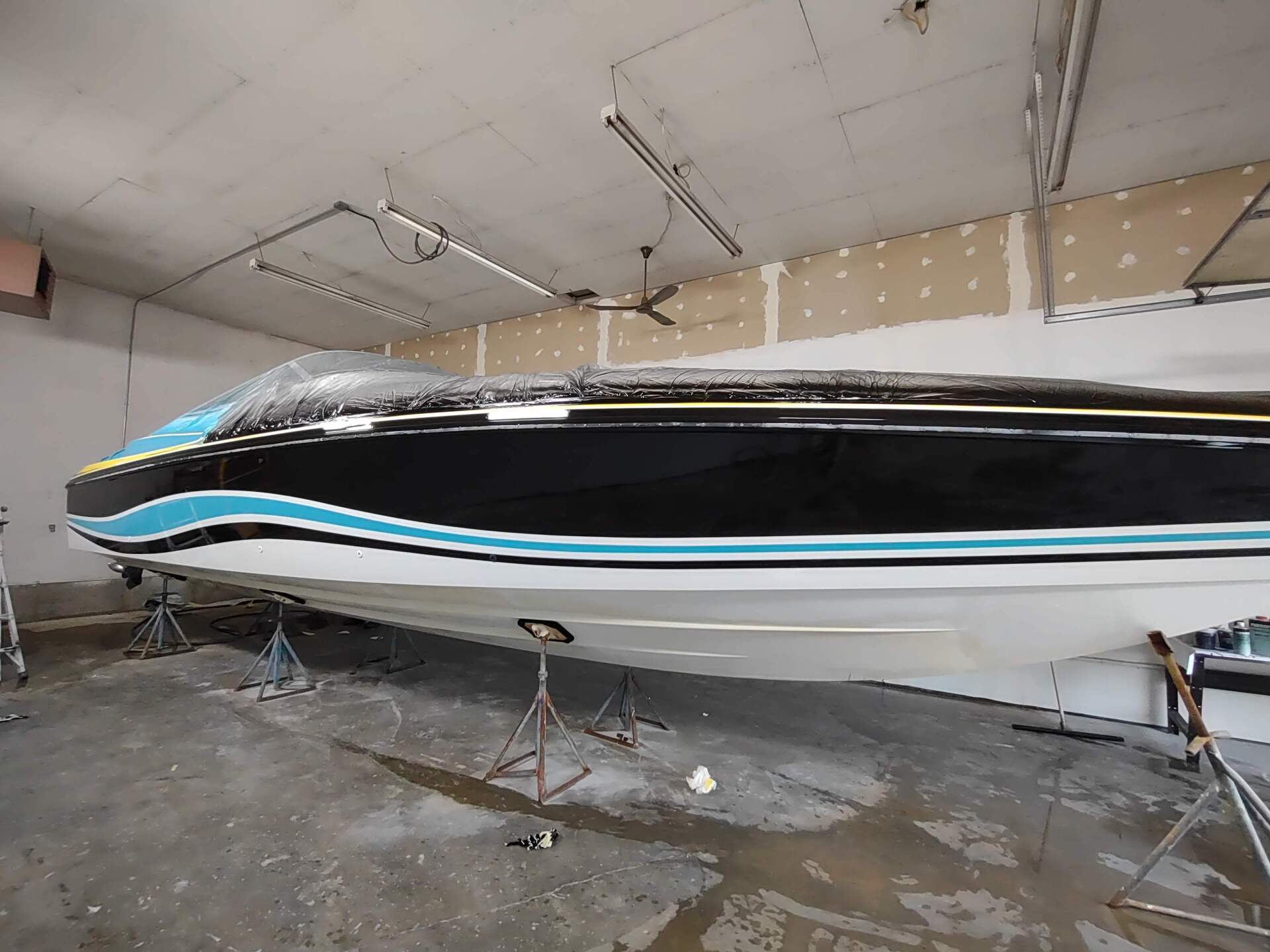 Black-and-white speedboat on stands inside a garage or workshop