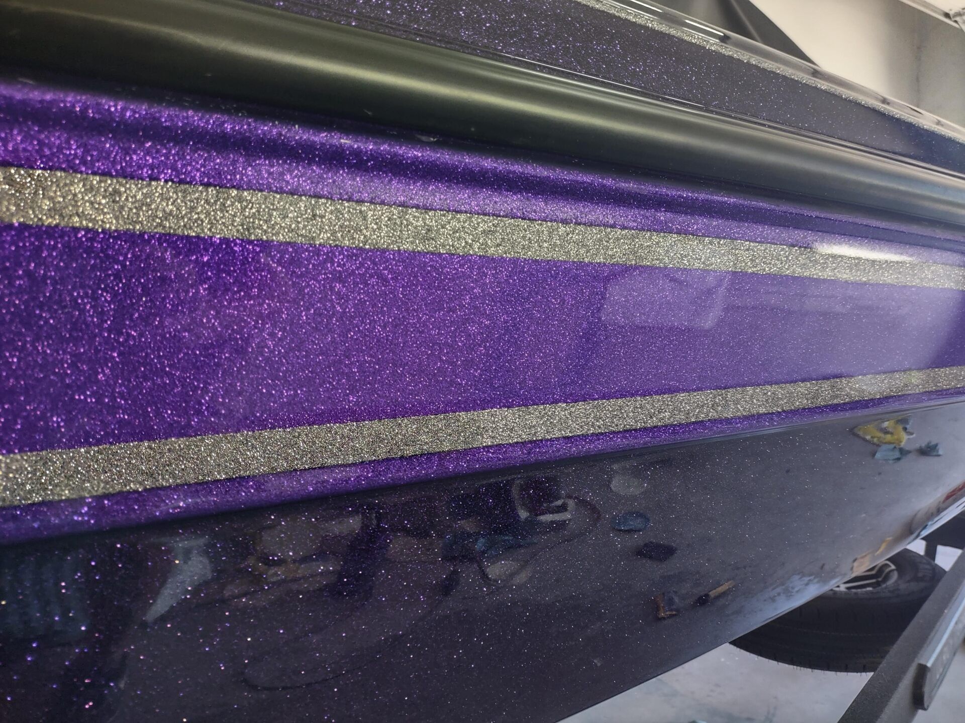 Purple glitter-striped boat hull with water droplets on a dark lower panel