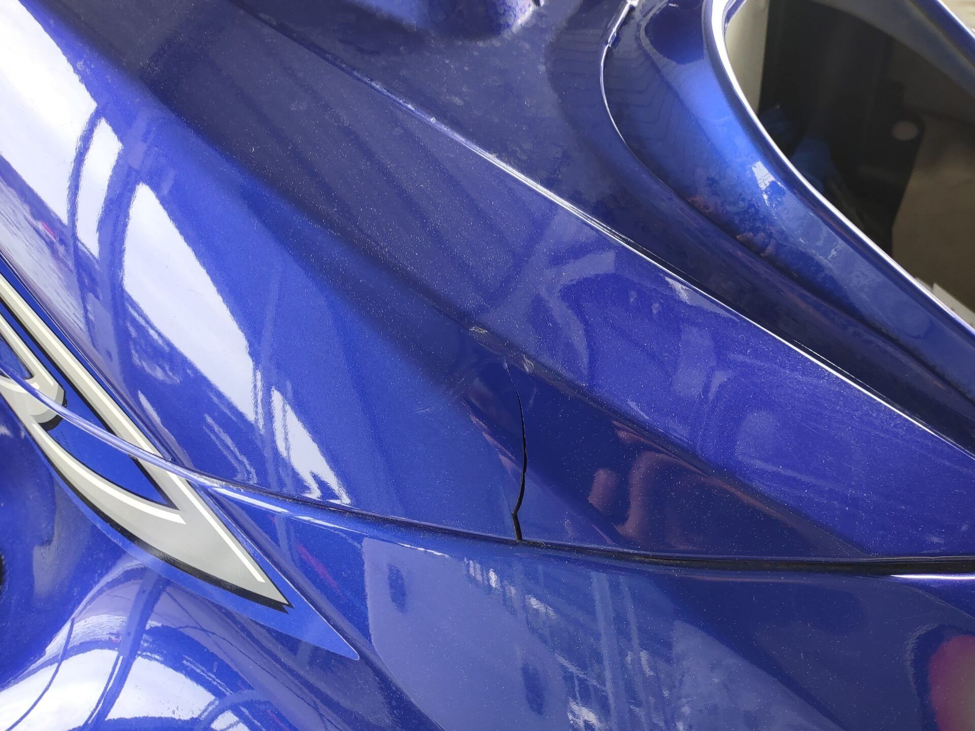 Close-up of a blue car’s side panel with a silver trim and reflections on the paint