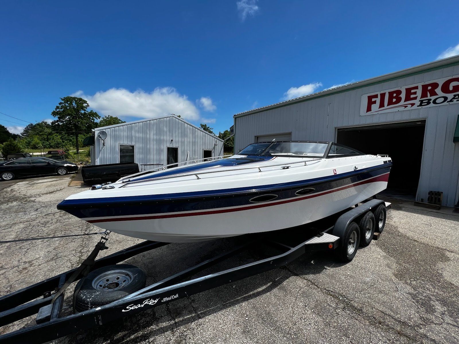 White-and-blue speedboat on a trailer outside a boat shop on a sunny day