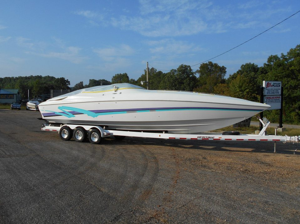 White speedboat on a trailer in a parking lot under a blue sky