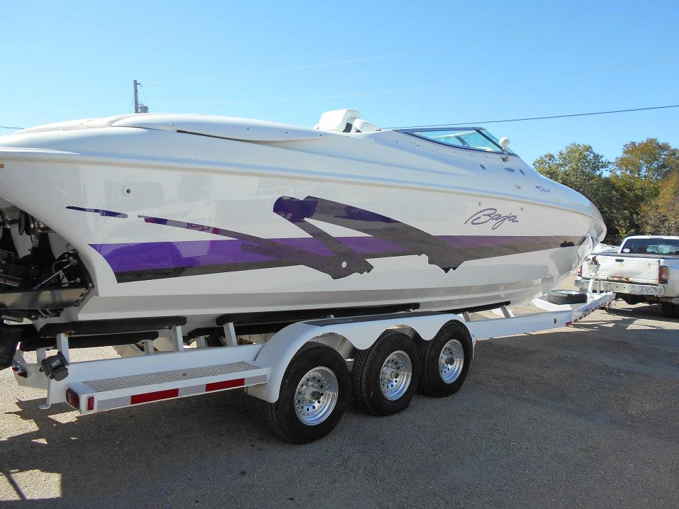 White and purple speedboat on a trailer in a sunny parking lot