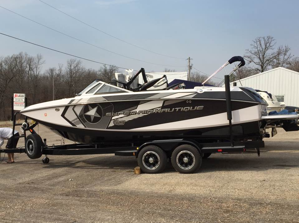 Black and white powerboat on a trailer, parked outdoors on a road under a gray sky