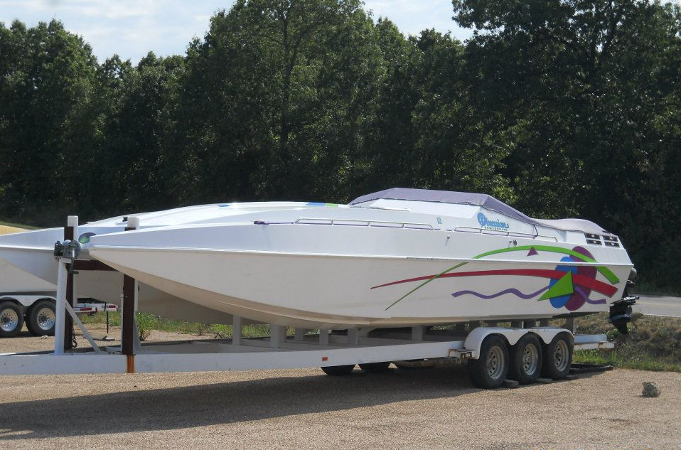White speedboat on trailer in a parking lot, with colorful graphics on the side.