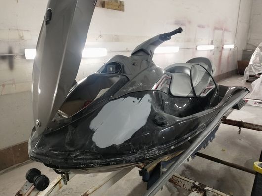 Black scooter with windshield and seat, parked indoors in a workshop or garage.