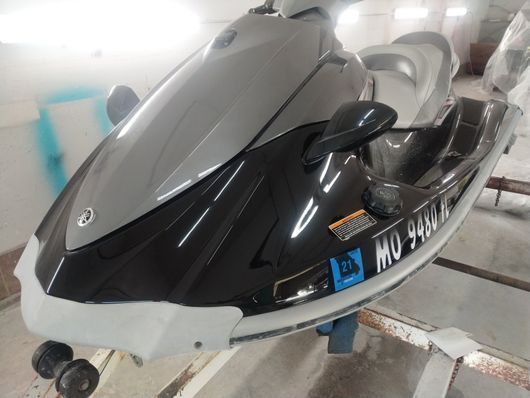 Parked black-and-gray jet ski with windshield and license plate in an indoor garage