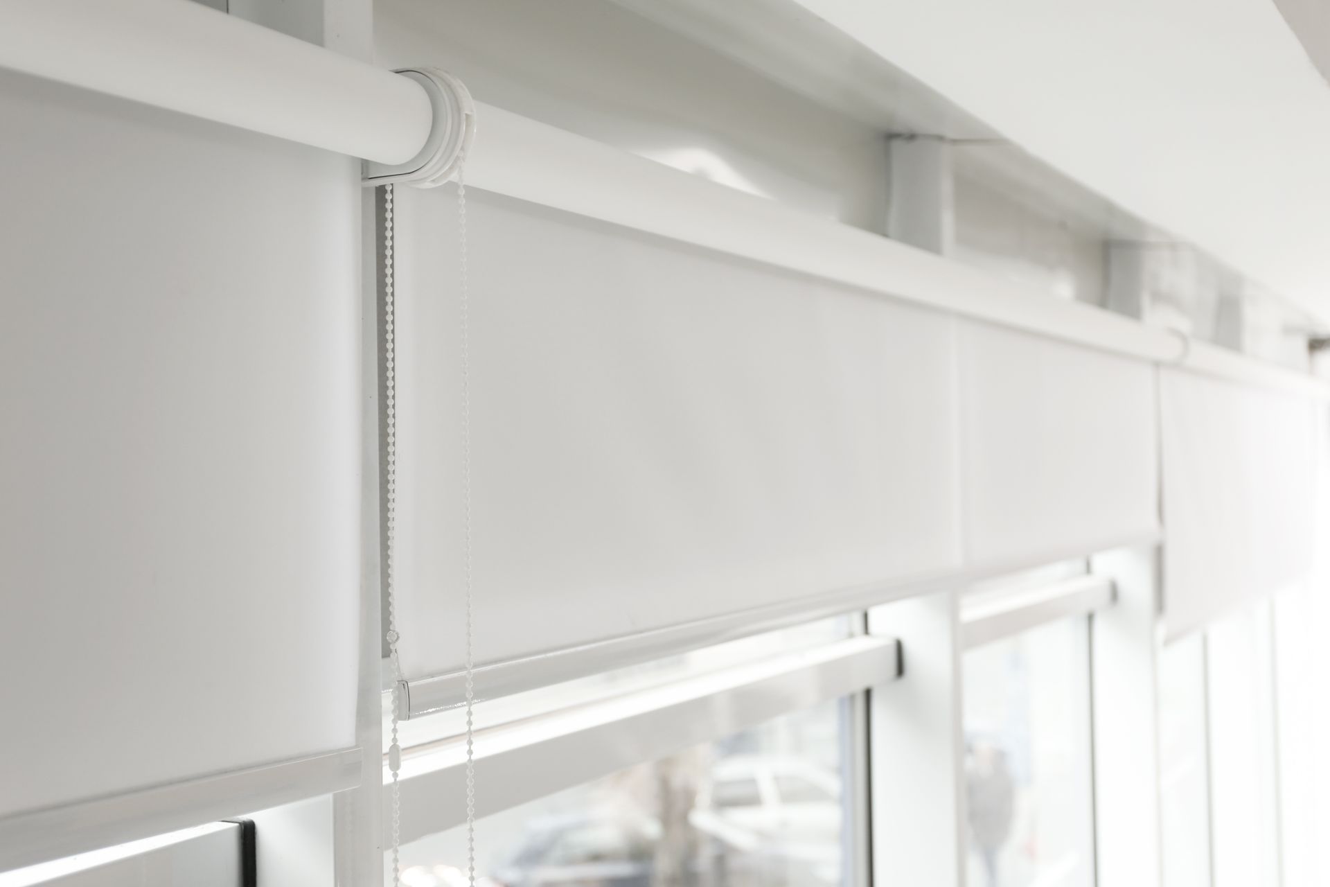 White roller blinds partially covering a window.
