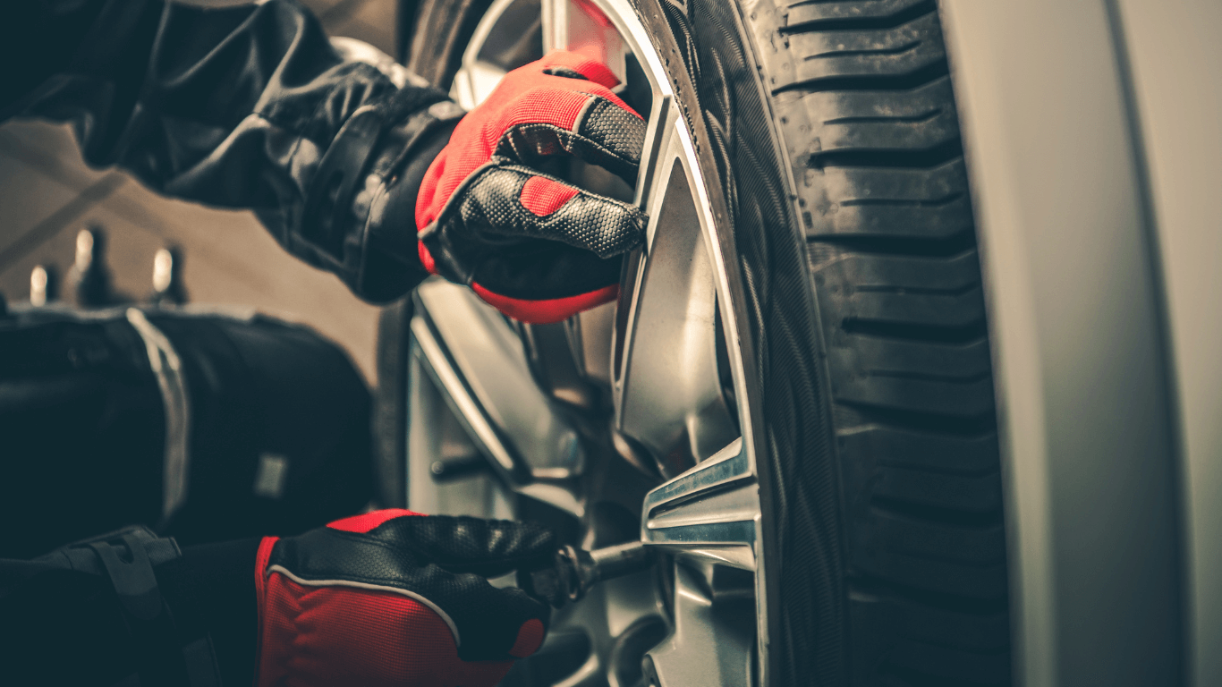 Tire rotation by a mechanic wearing red gloves
