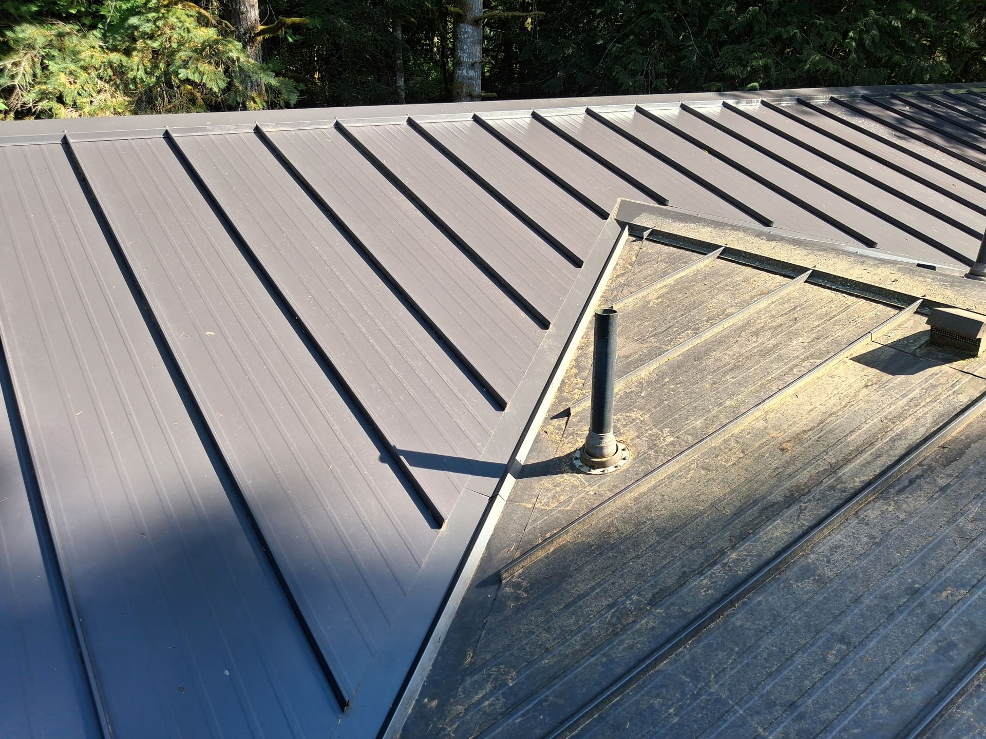 Rooftop with a metal roof and an open skylight or vent frame at the right edge.