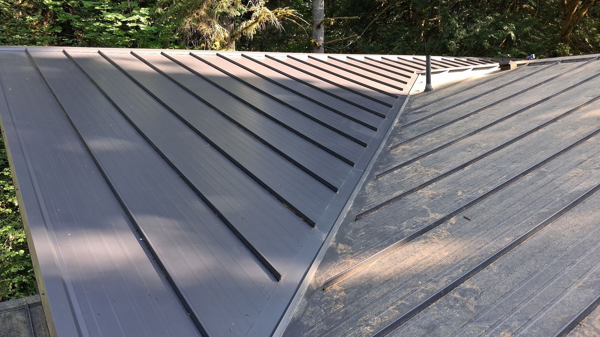 Metal roof with two sloped sections meeting at a central valley, viewed from above.