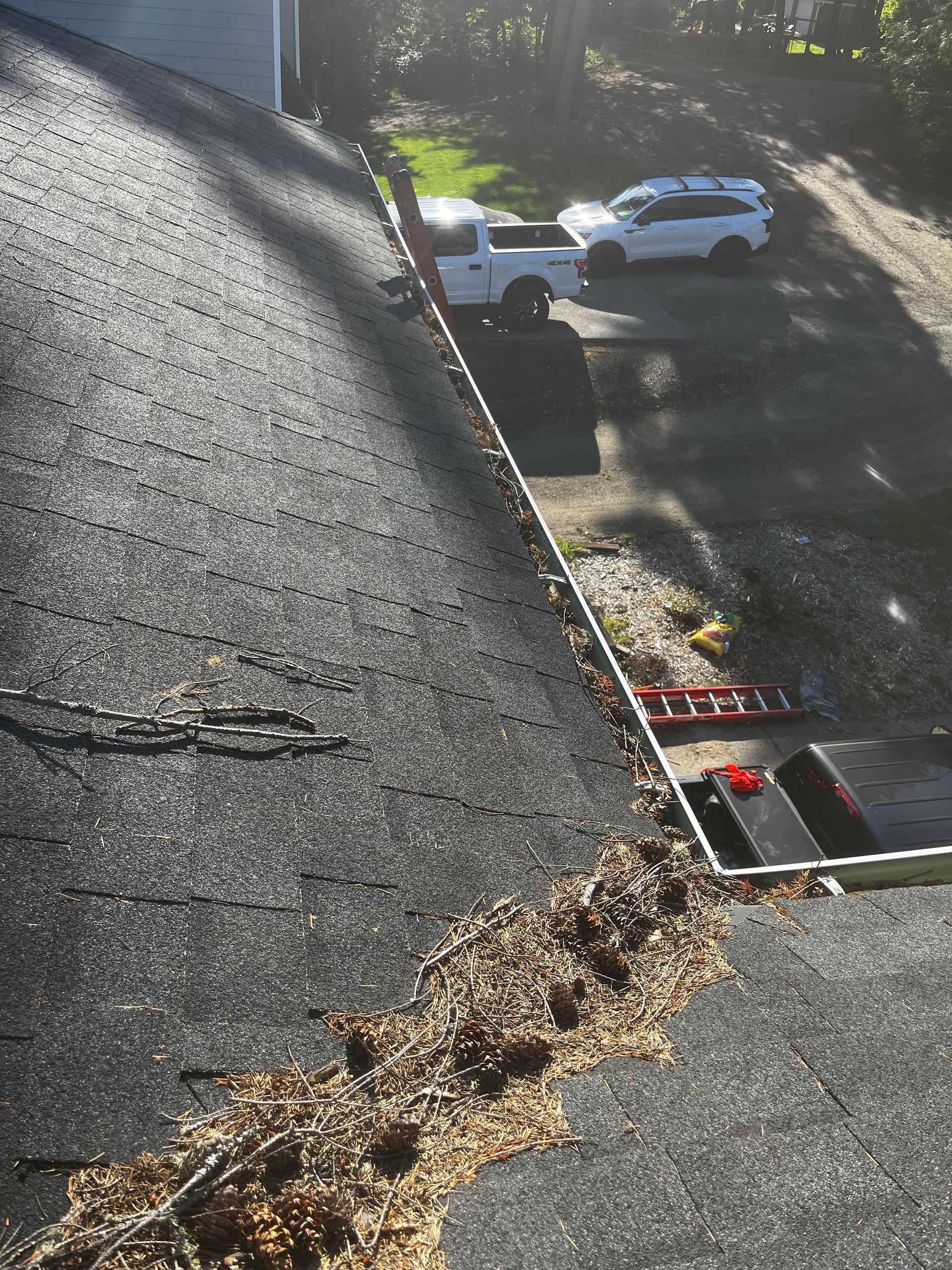 Damaged roof with a large crack and debris, overlooking a street with parked cars below.