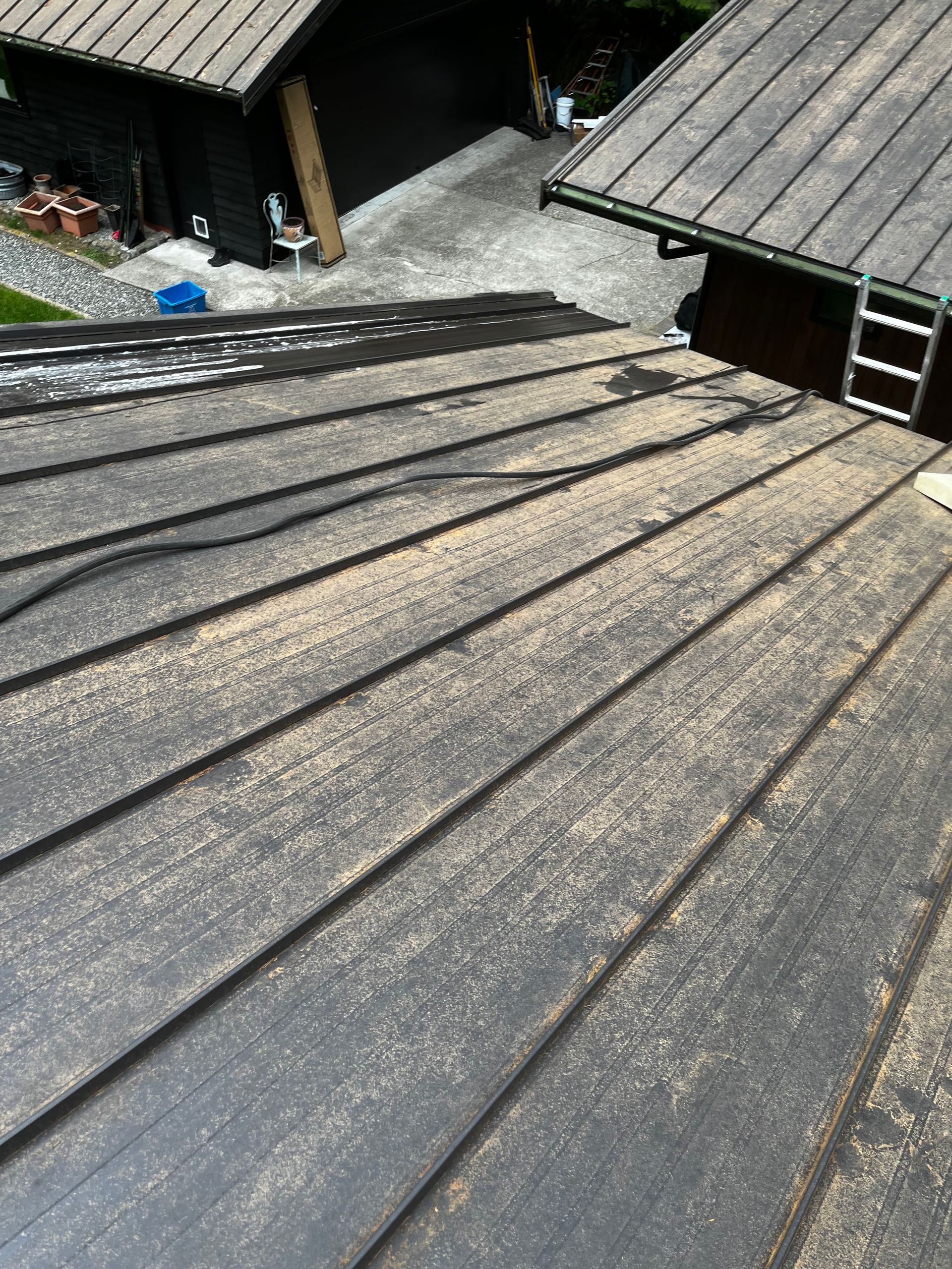 Weathered shingle roof in foreground, with buildings and courtyard below.
