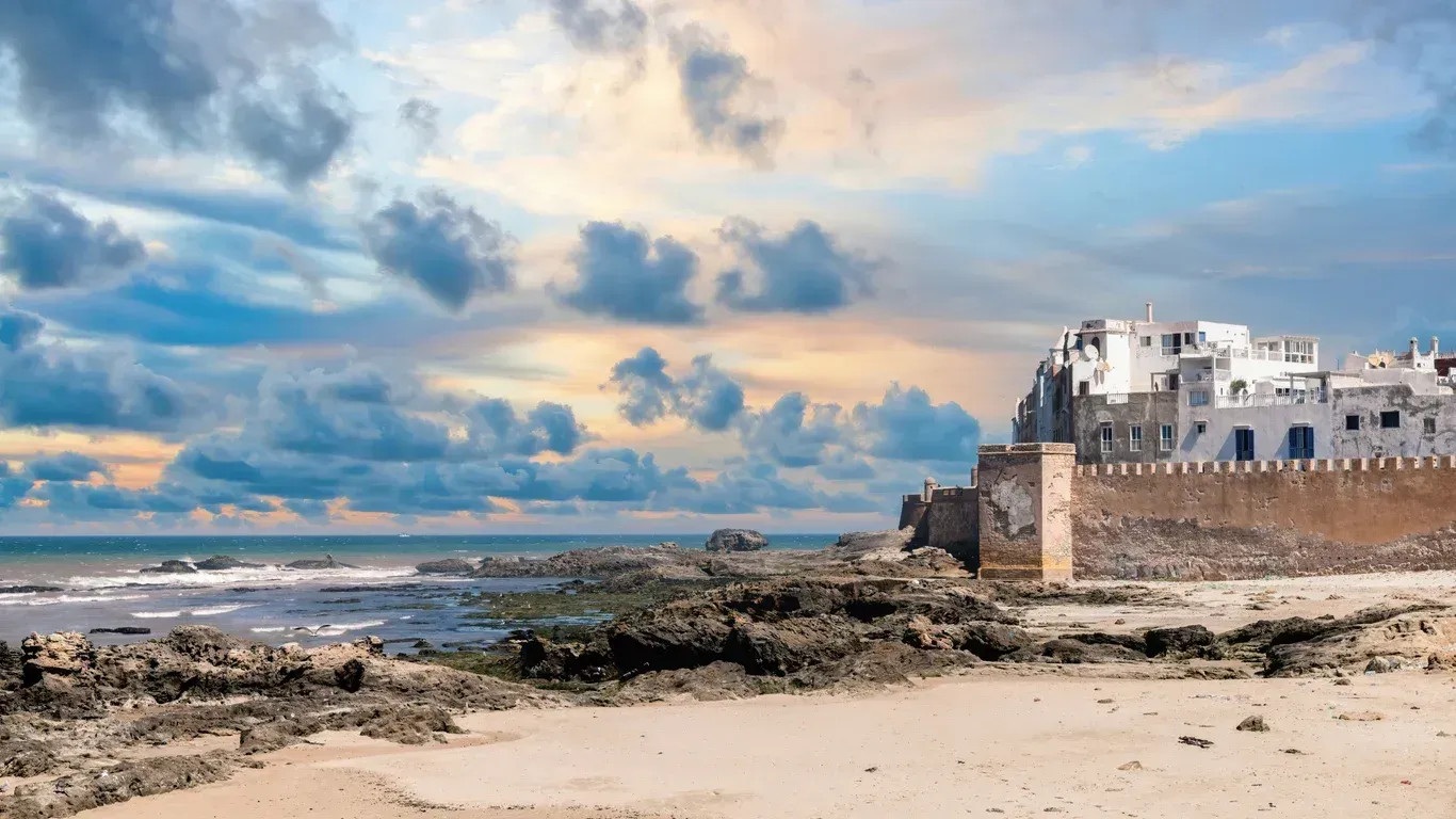 A castle is sitting on top of a sandy beach next to the ocean.