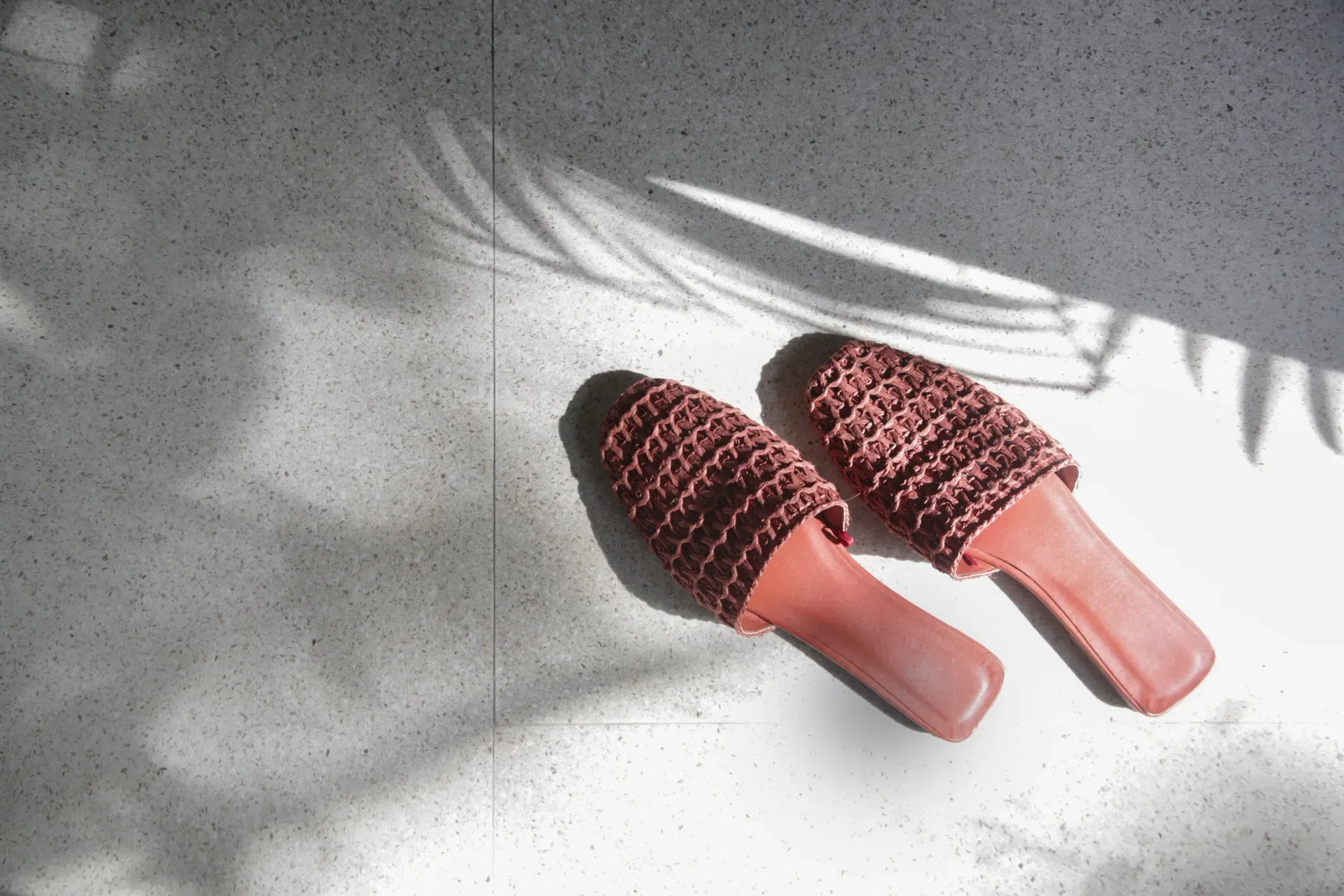 A pair of red sandals are sitting on a white surface.