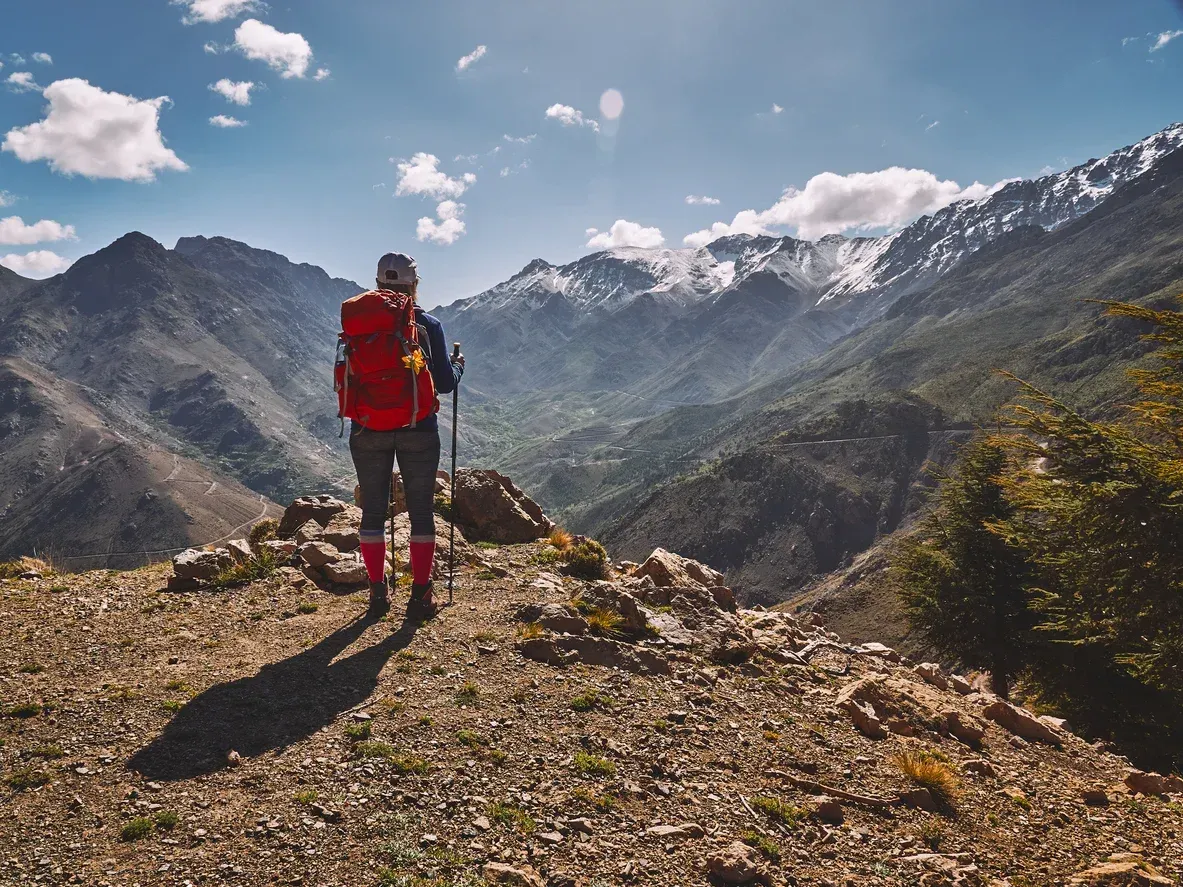 A person with a backpack is standing on top of a mountain.