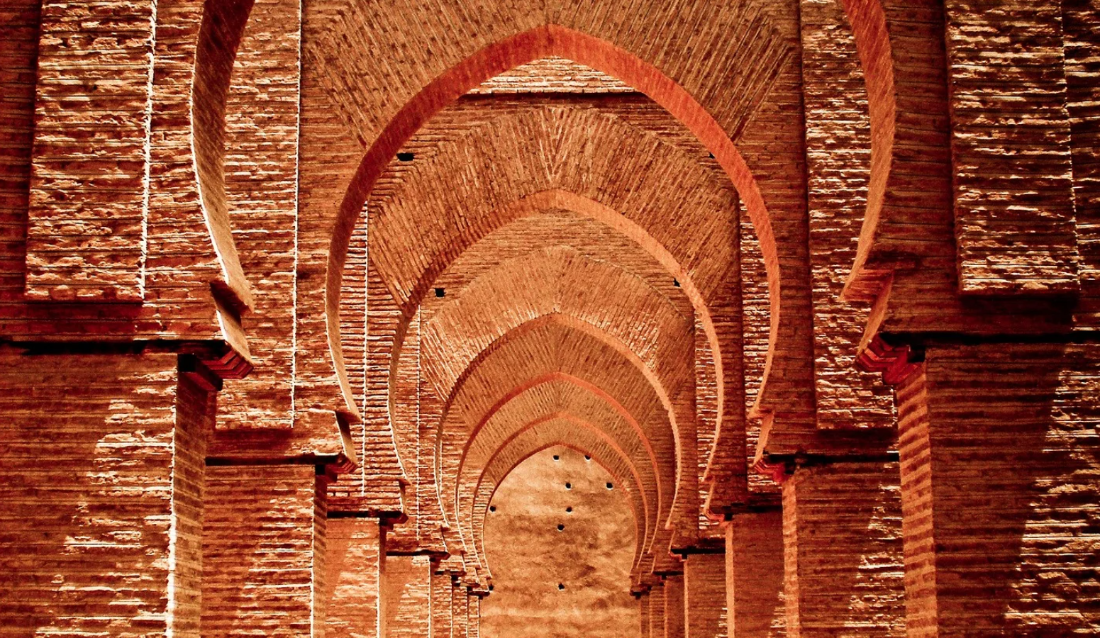 A long hallway with arches and columns made of bricks.