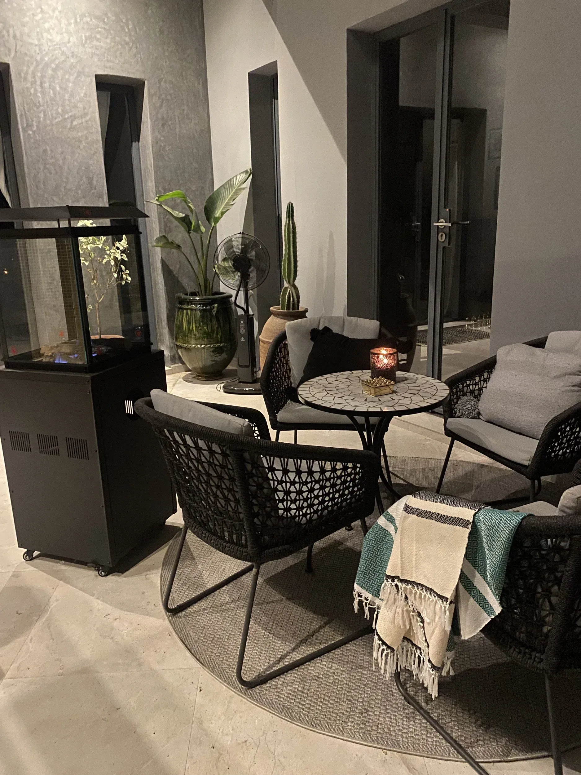 A patio with chairs , a table and a heater.