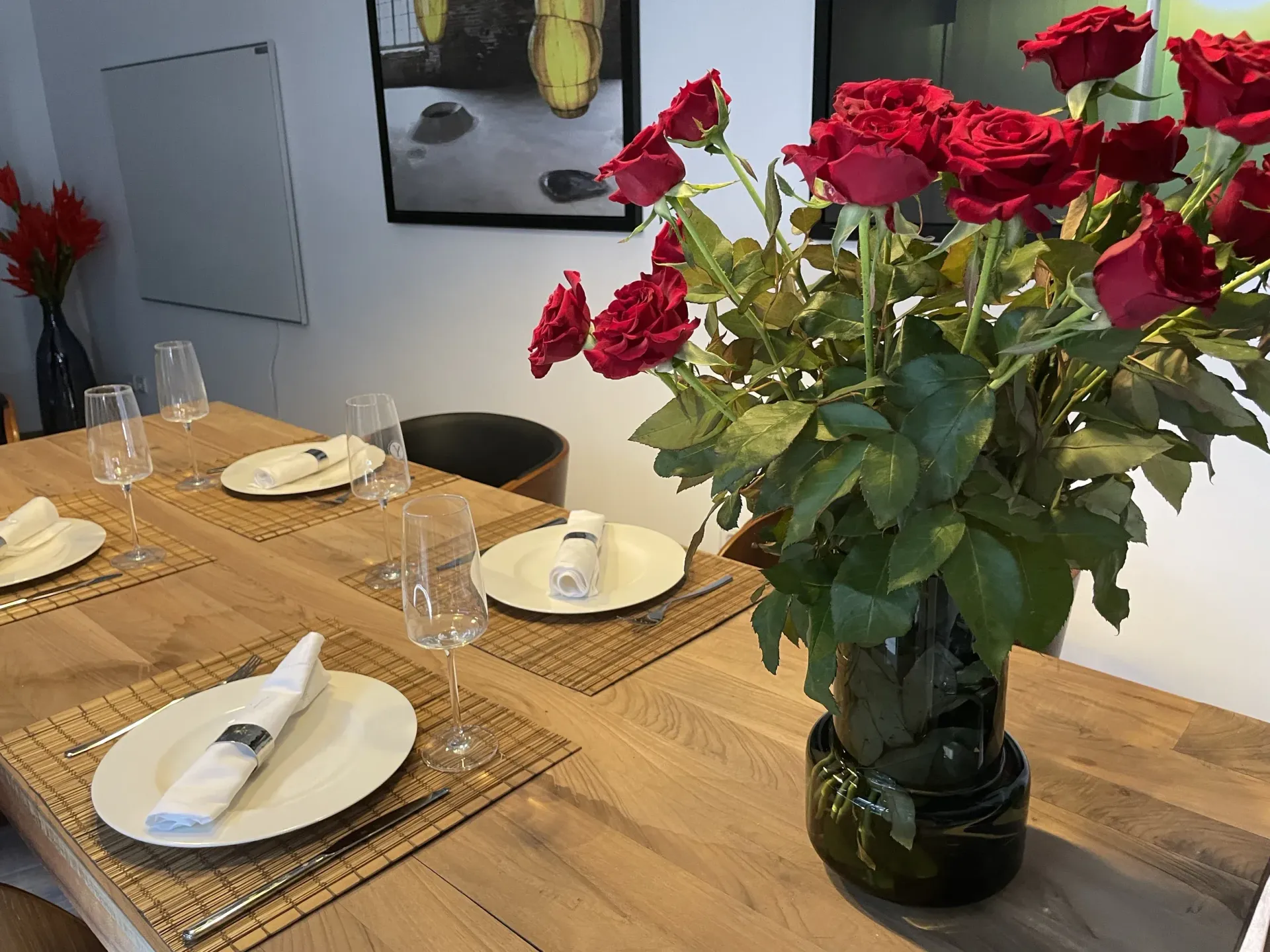 A vase of red roses is sitting on a wooden table.