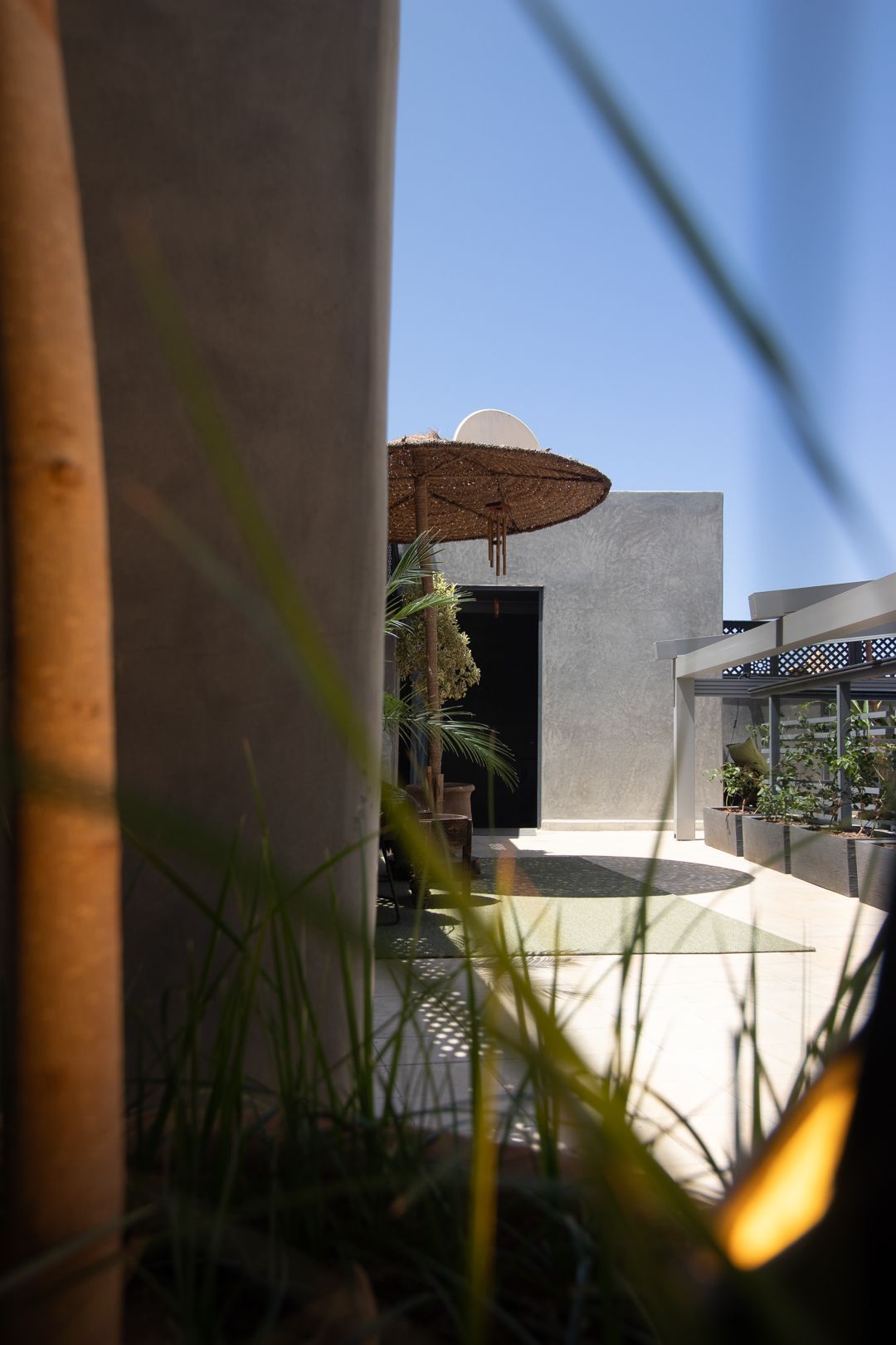 A patio with a straw umbrella in the background