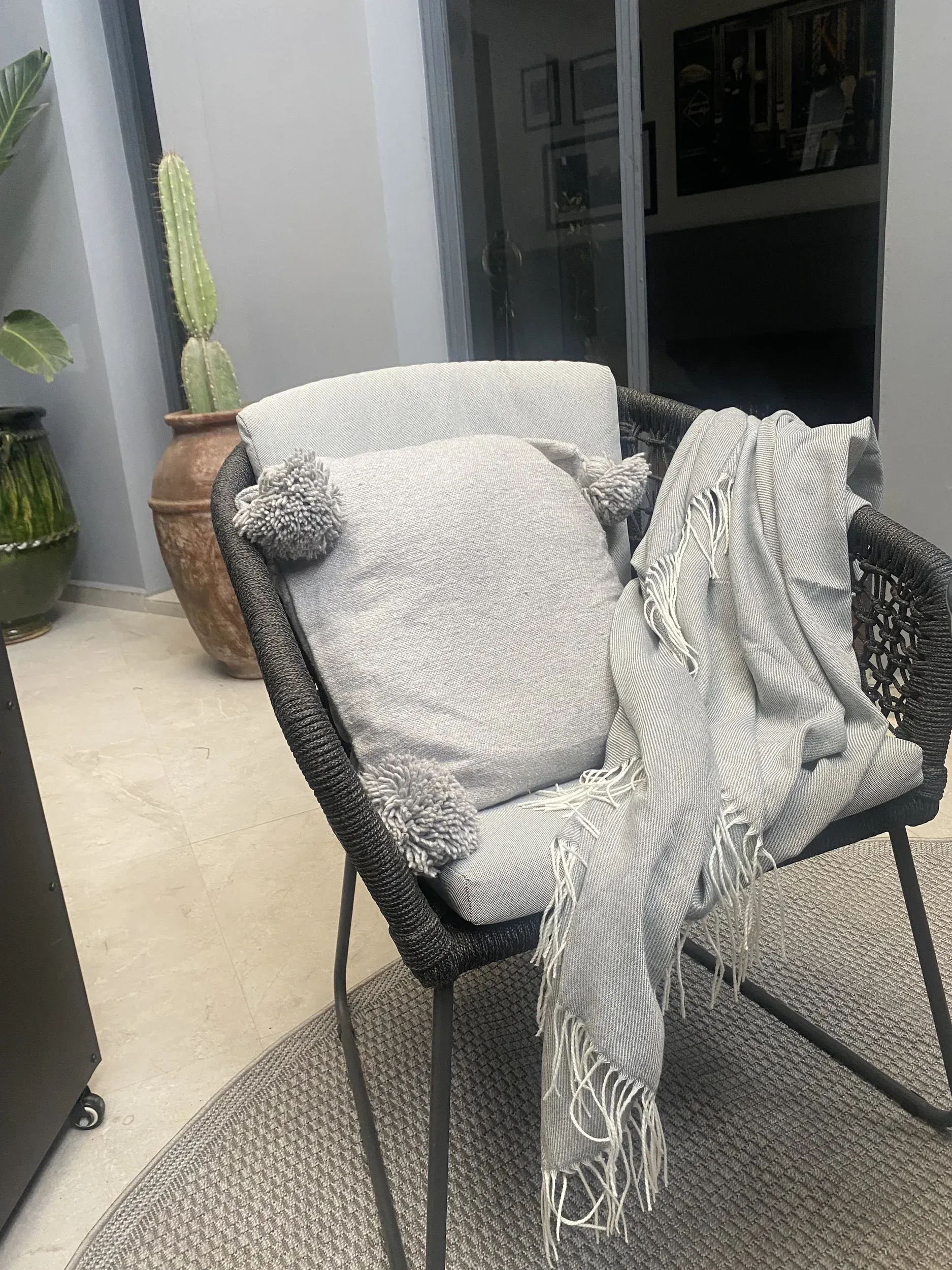 A chair with a blanket on it is sitting on a rug.