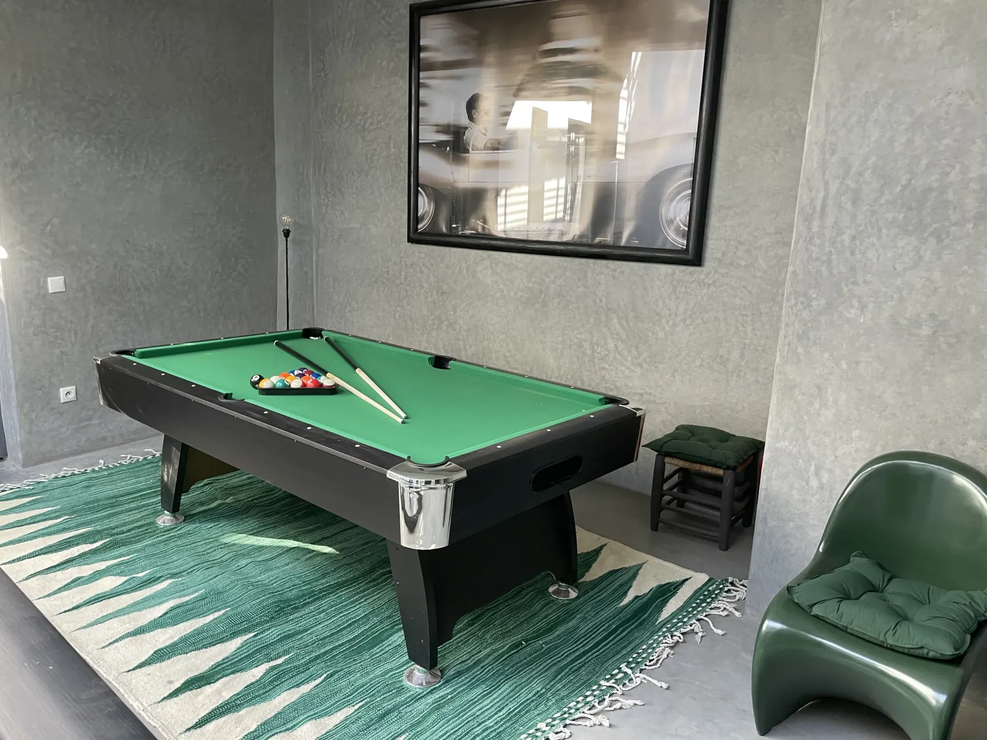 A pool table in a room with a picture on the wall above it