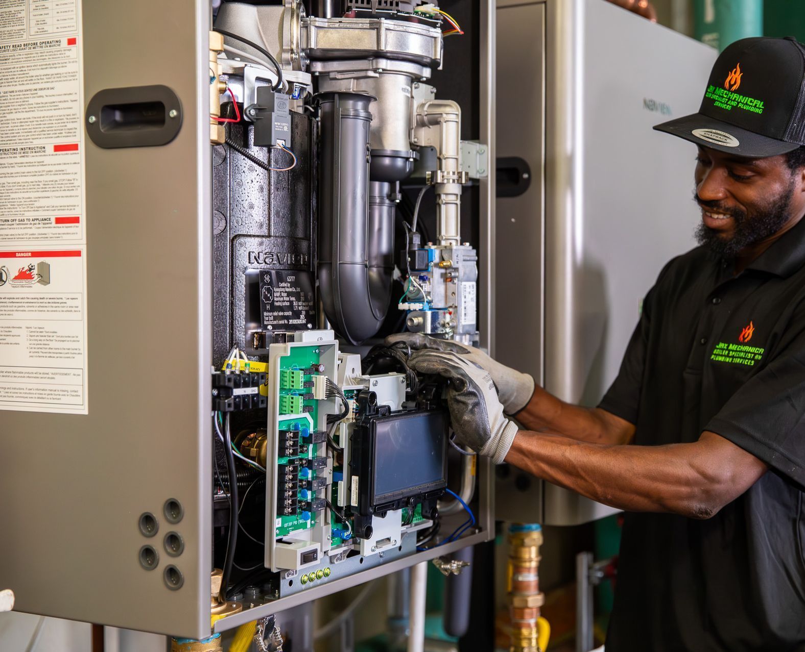 Technician inspecting furnace components inside an open HVAC unit with exposed wiring and metal pipes