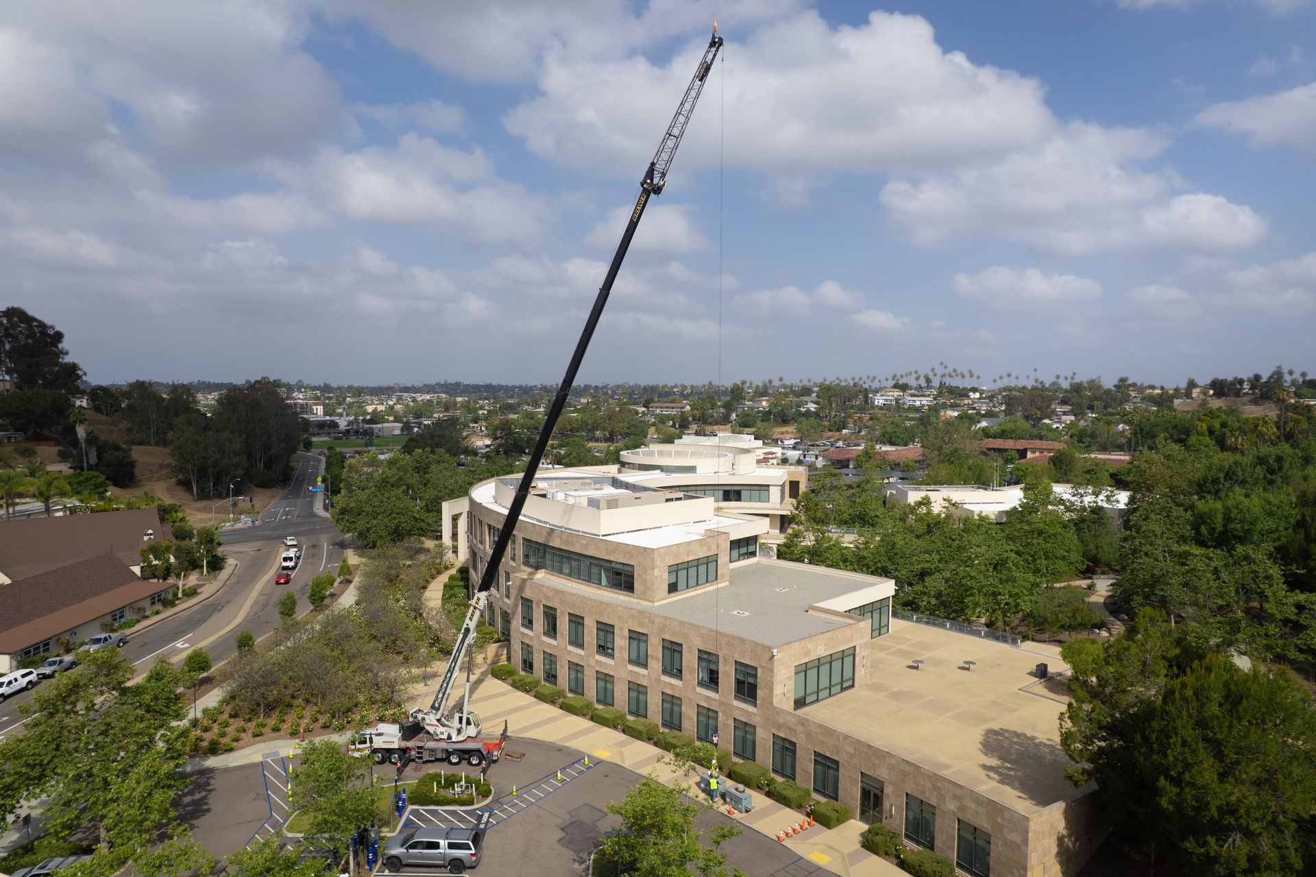 Construction crane towering over a tan building in a suburban neighborhood under a cloudy sky