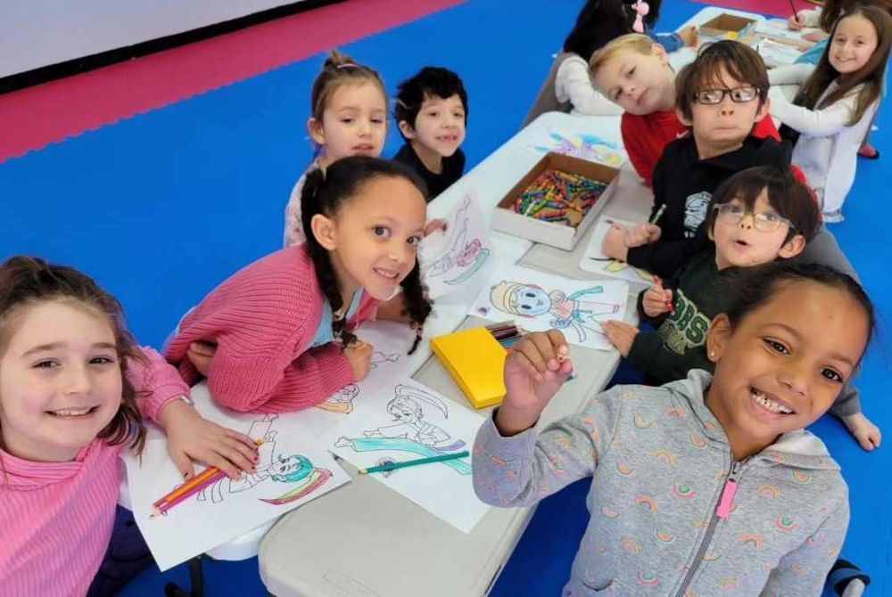 A group of children are sitting at a table drawing.