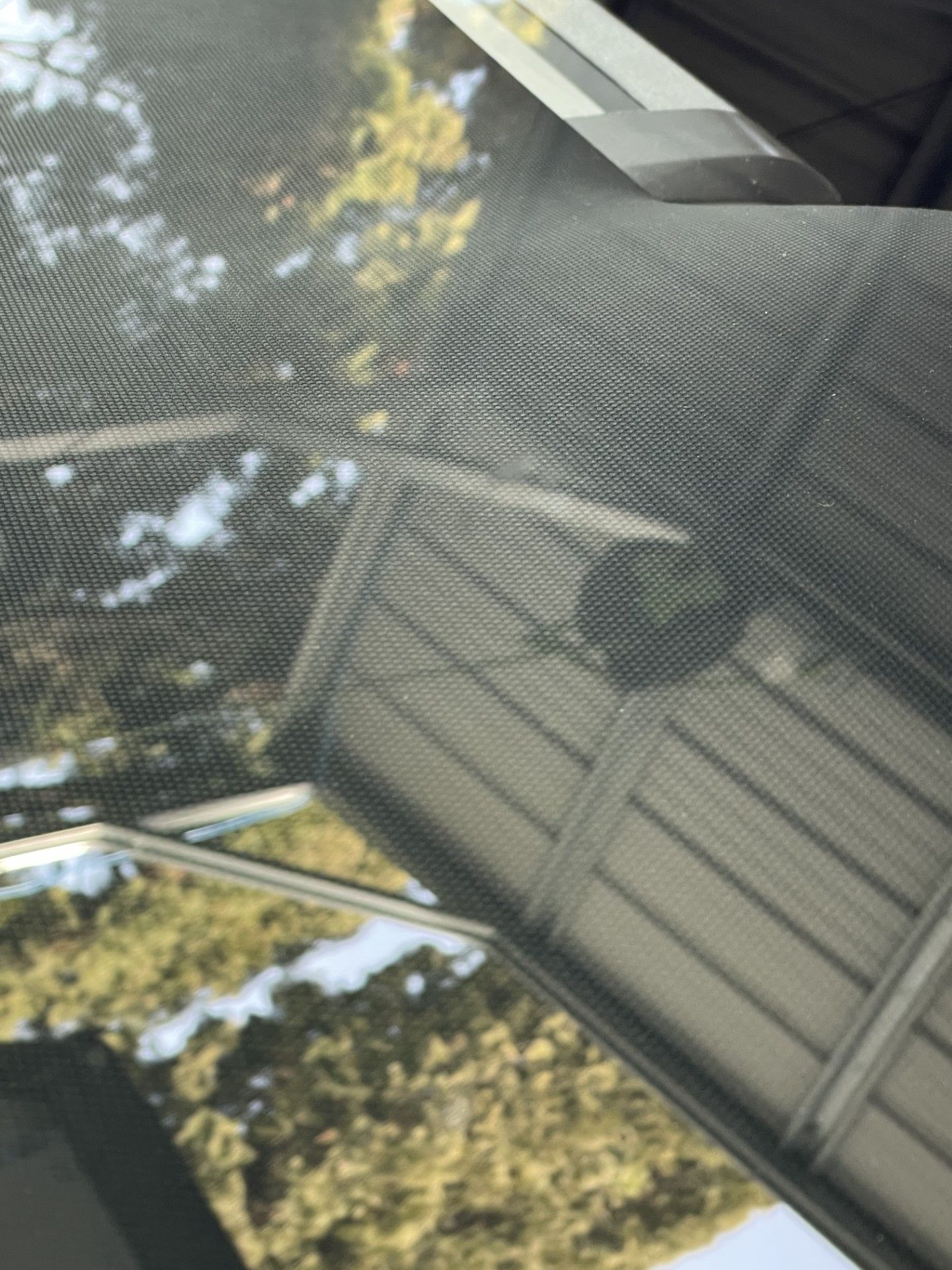 A close up of a screen door with a reflection of a house in it.
