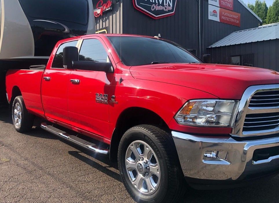 Red Ram 2500 truck towing a trailer parked in front of a business.