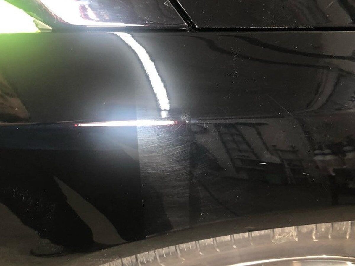 A close up of a black car with a reflection showing PPF protection