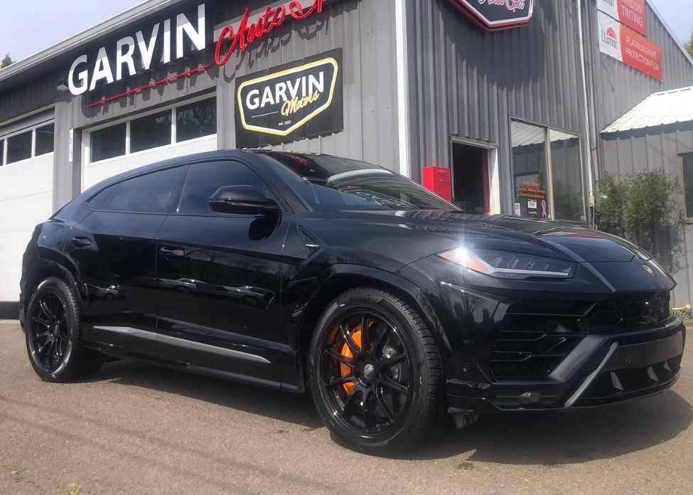 Black sports SUV parked outside a Garvin dealership, with orange brake calipers and black rims.