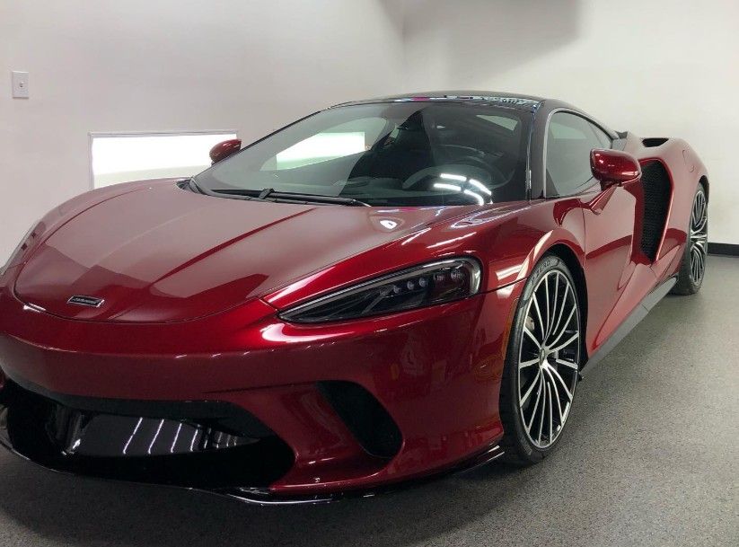 Red McLaren GT sports car in a showroom.
