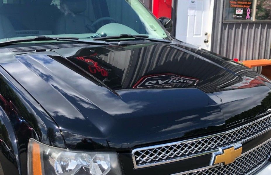 Black Chevrolet SUV hood reflecting surroundings, including a building and logo.